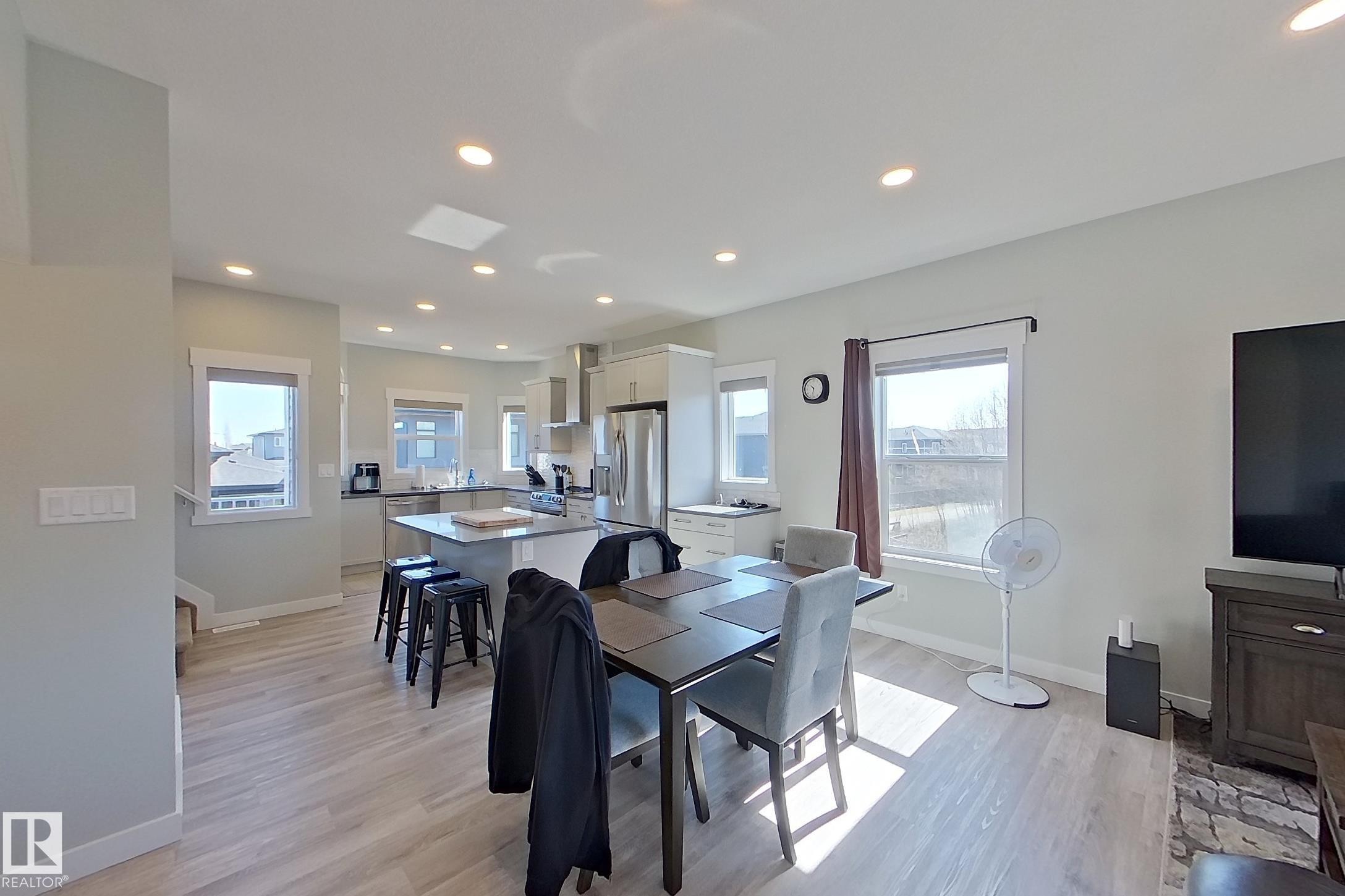 Open-concept living area featuring wood-finish flooring, recessed ceiling lighting, and multiple windows - 33 150 Everitt Dr, St. Albert, AB - Indoor Photo Showing Dining Room