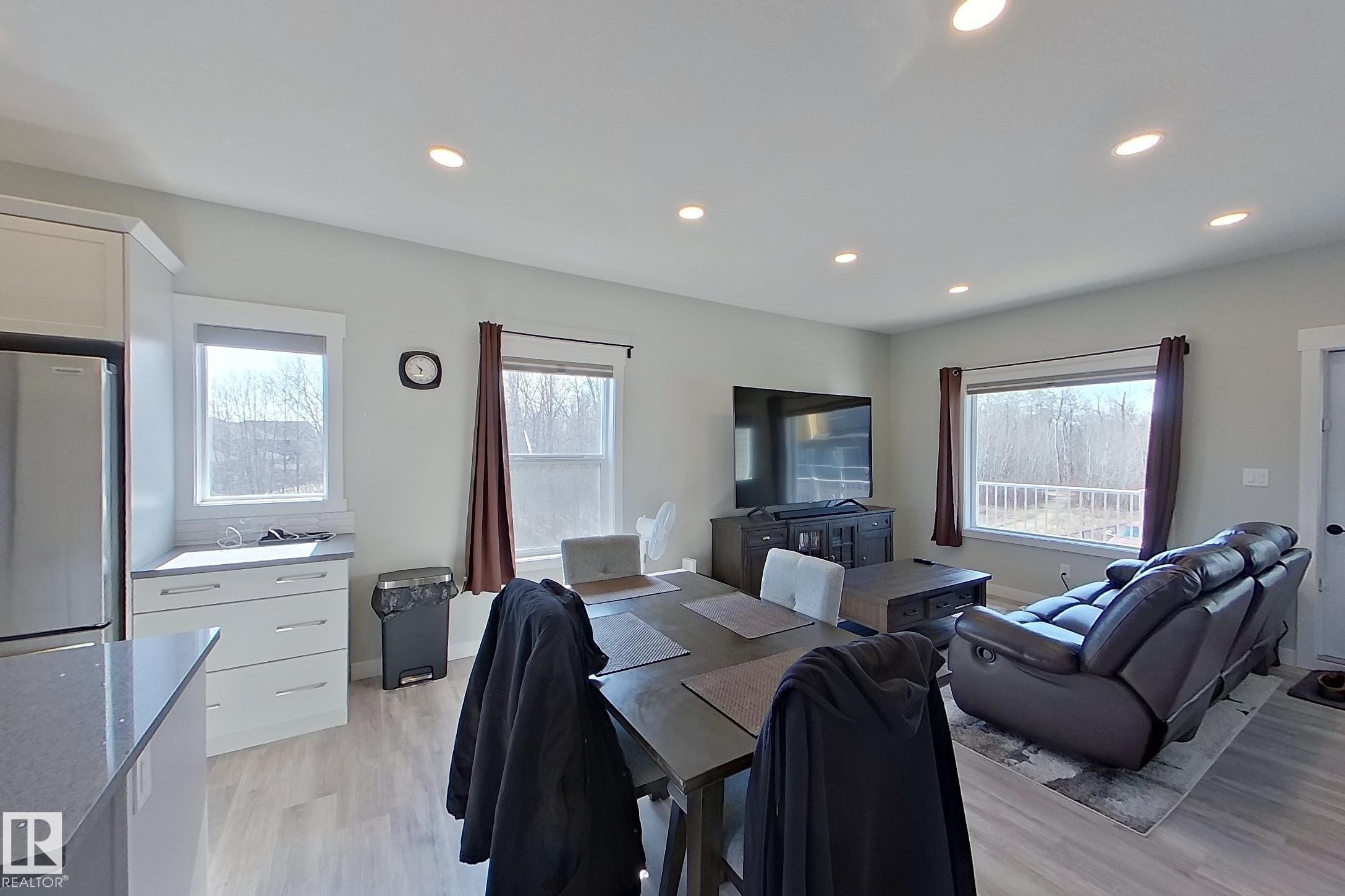 Open-concept living space featuring recessed lighting, light-toned wood-finish flooring, and multiple windows - 33 150 Everitt Dr, St. Albert, AB - Indoor