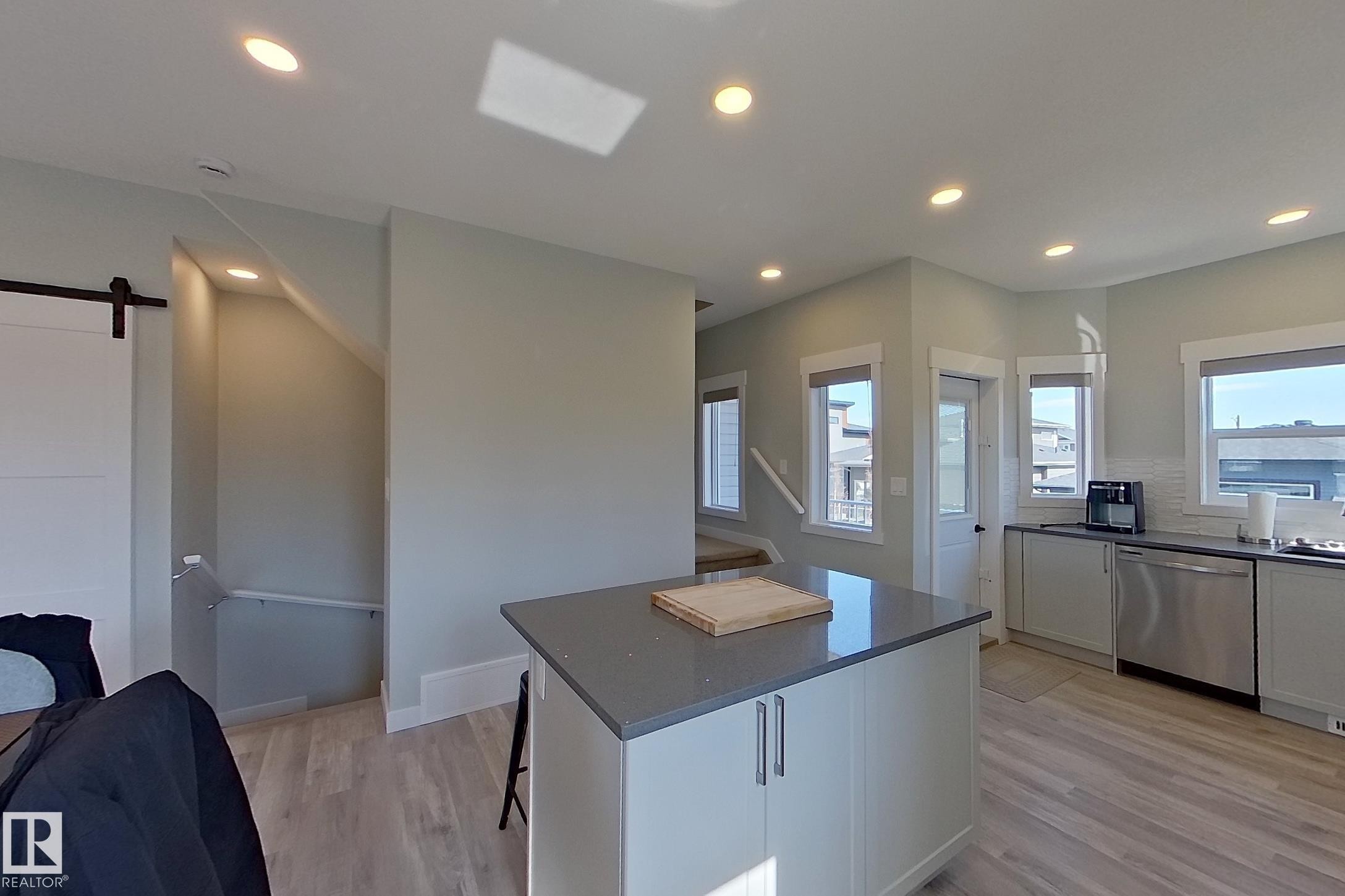 Kitchen featuring a central island with a solid surface countertop and light-toned cabinetry - 33 150 Everitt Dr, St. Albert, AB - Indoor Photo Showing Kitchen