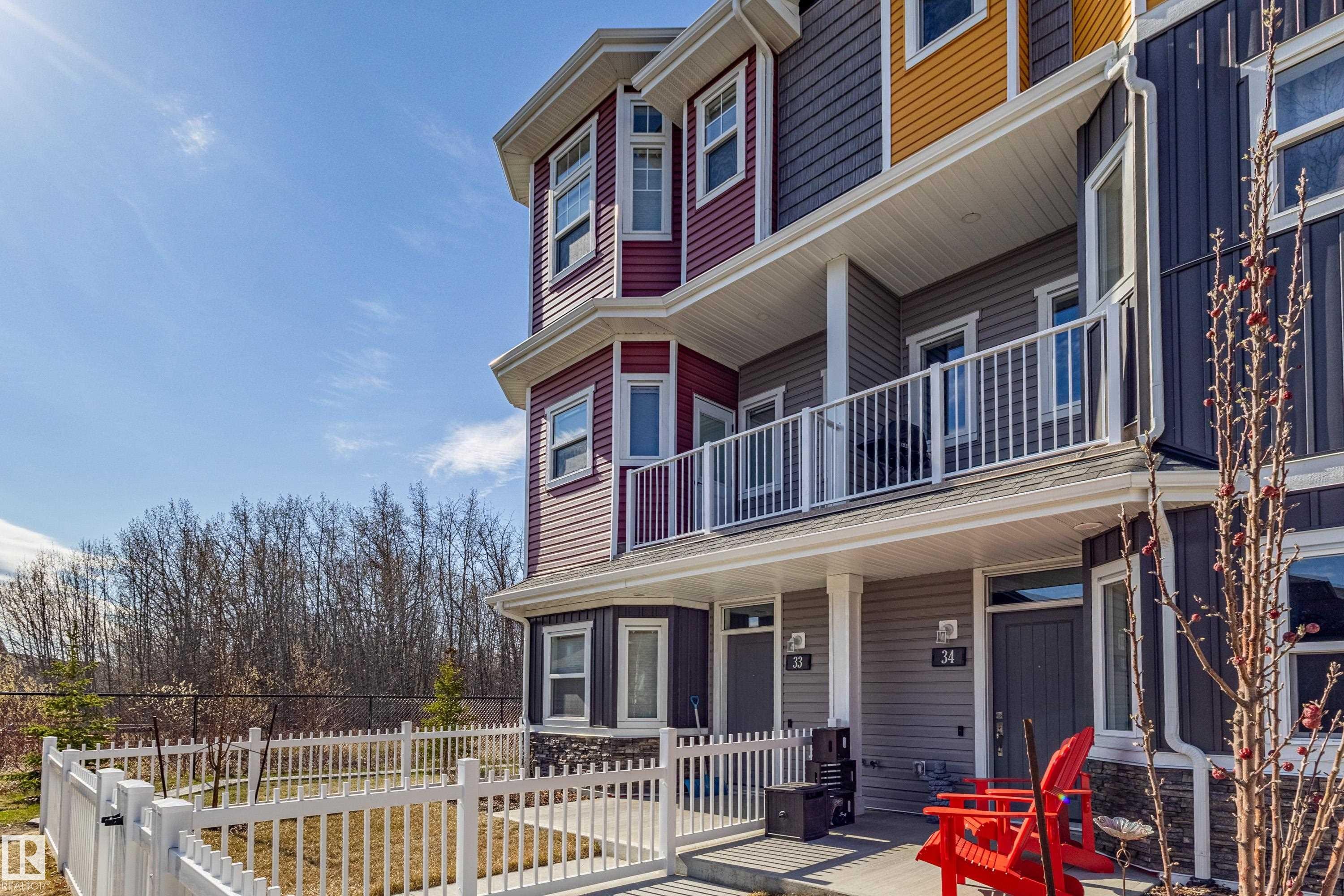 Multi-story townhome exterior featuring red, grey, and yellow siding - 33 150 Everitt Dr, St. Albert, AB - Outdoor With Deck Patio Veranda