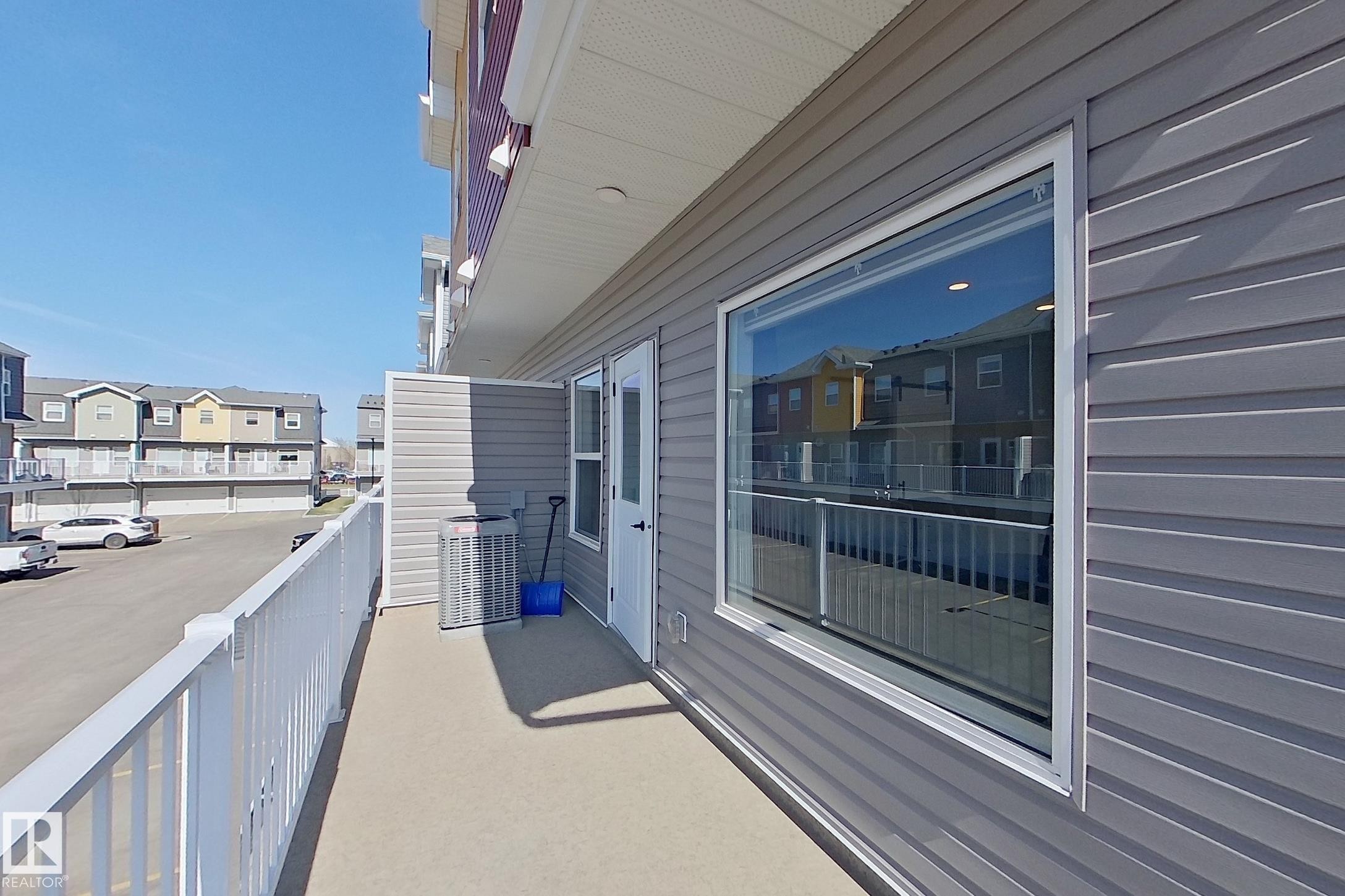 Upper-level balcony featuring a white railing and textured exterior siding - 33 150 Everitt Dr, St. Albert, AB - Outdoor