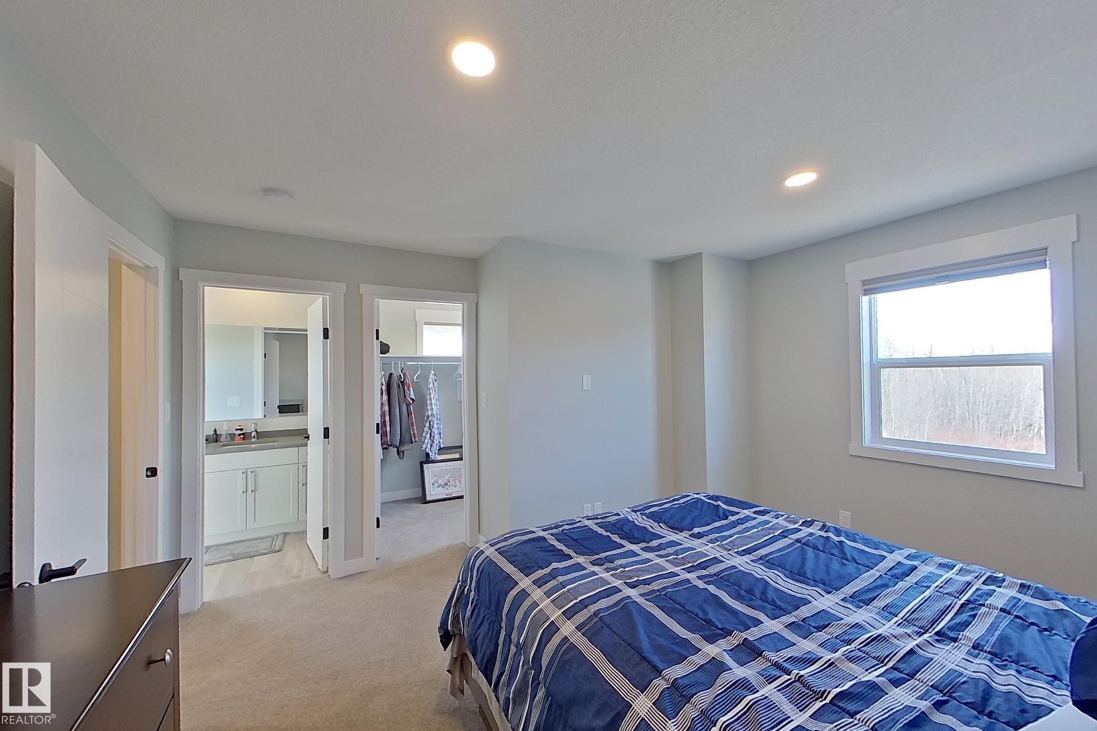 Carpeted bedroom with recessed lighting, a large window, and direct access to a separate bathroom and walk-in closet - 33 150 Everitt Dr, St. Albert, AB - Indoor Photo Showing Bedroom