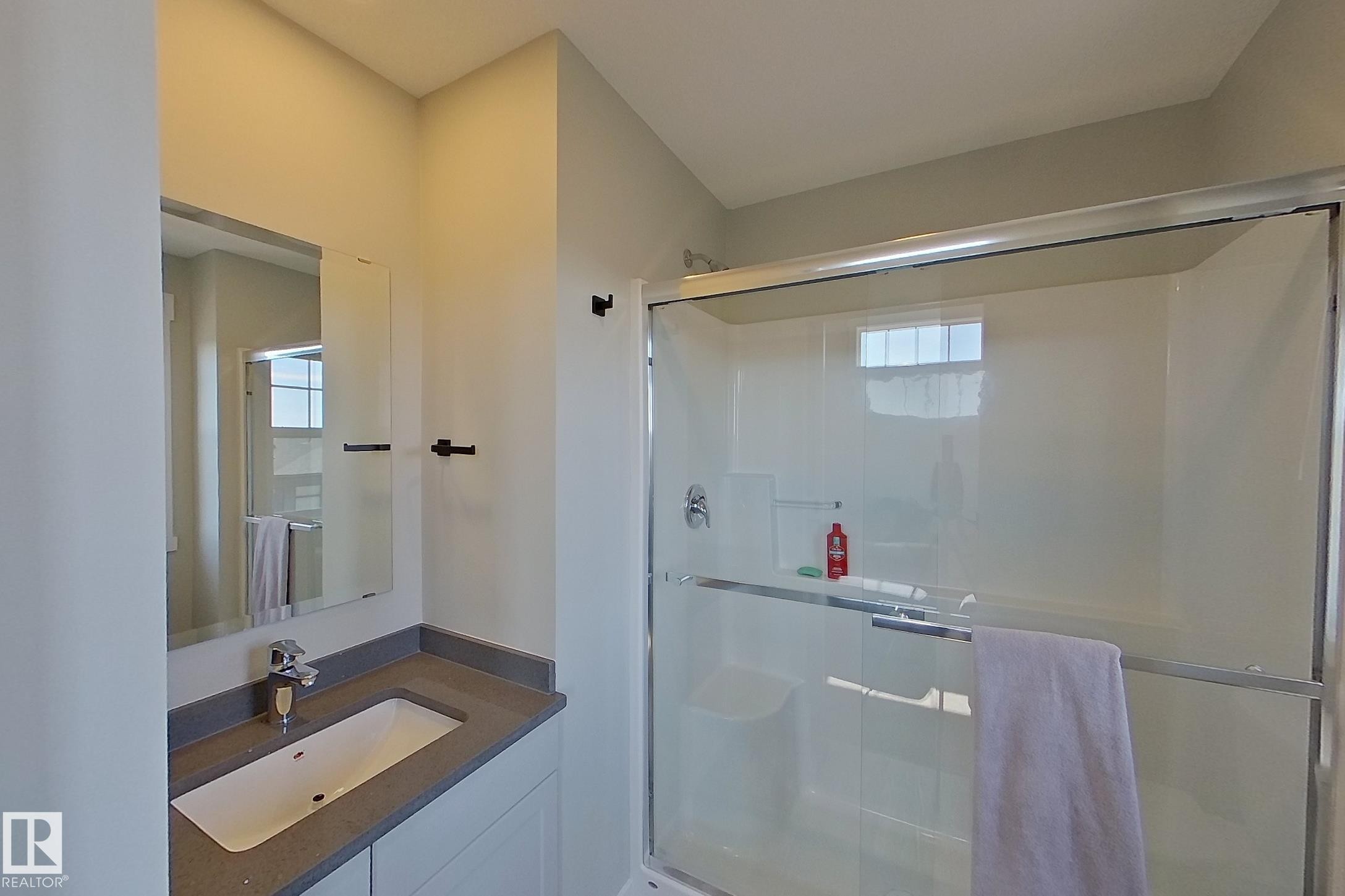 Bathroom featuring a vanity with an undermount sink, a dark countertop, and a framed mirror - 33 150 Everitt Dr, St. Albert, AB - Indoor Photo Showing Bathroom