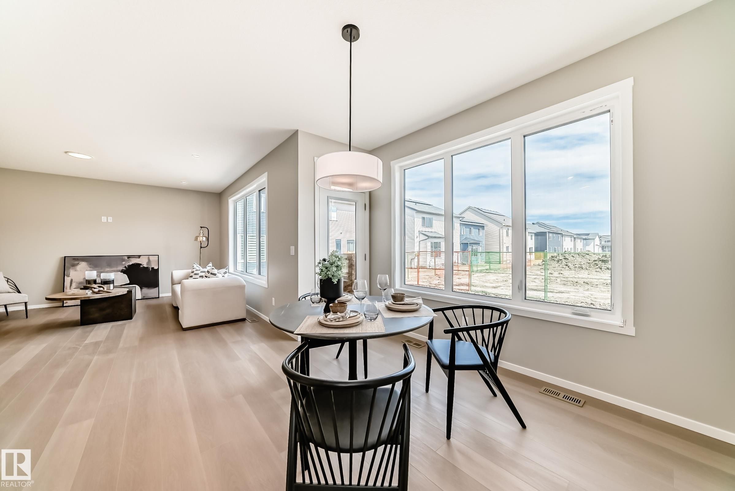 Open-concept living space featuring wood-finish flooring, a large multi-pane window, and light neutral wall tones - 1603 206 Street, Edmonton, AB - Indoor