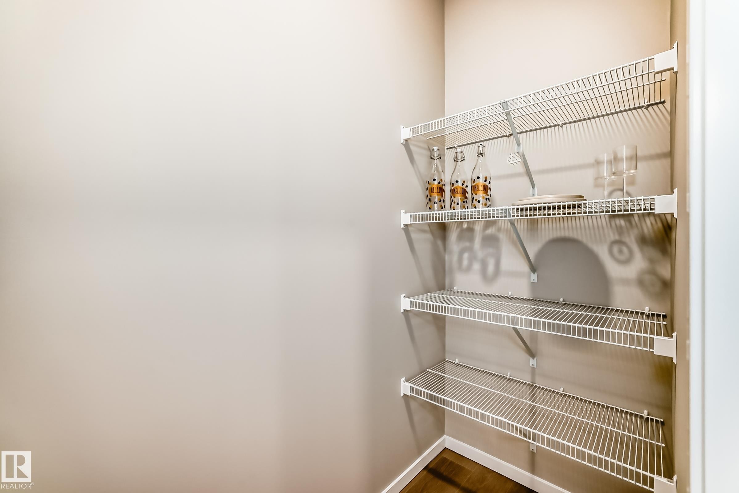 Corner pantry featuring three levels of wire shelving, light neutral wall paint, and wood-finish flooring - 1603 206 Street, Edmonton, AB - Indoor With Storage