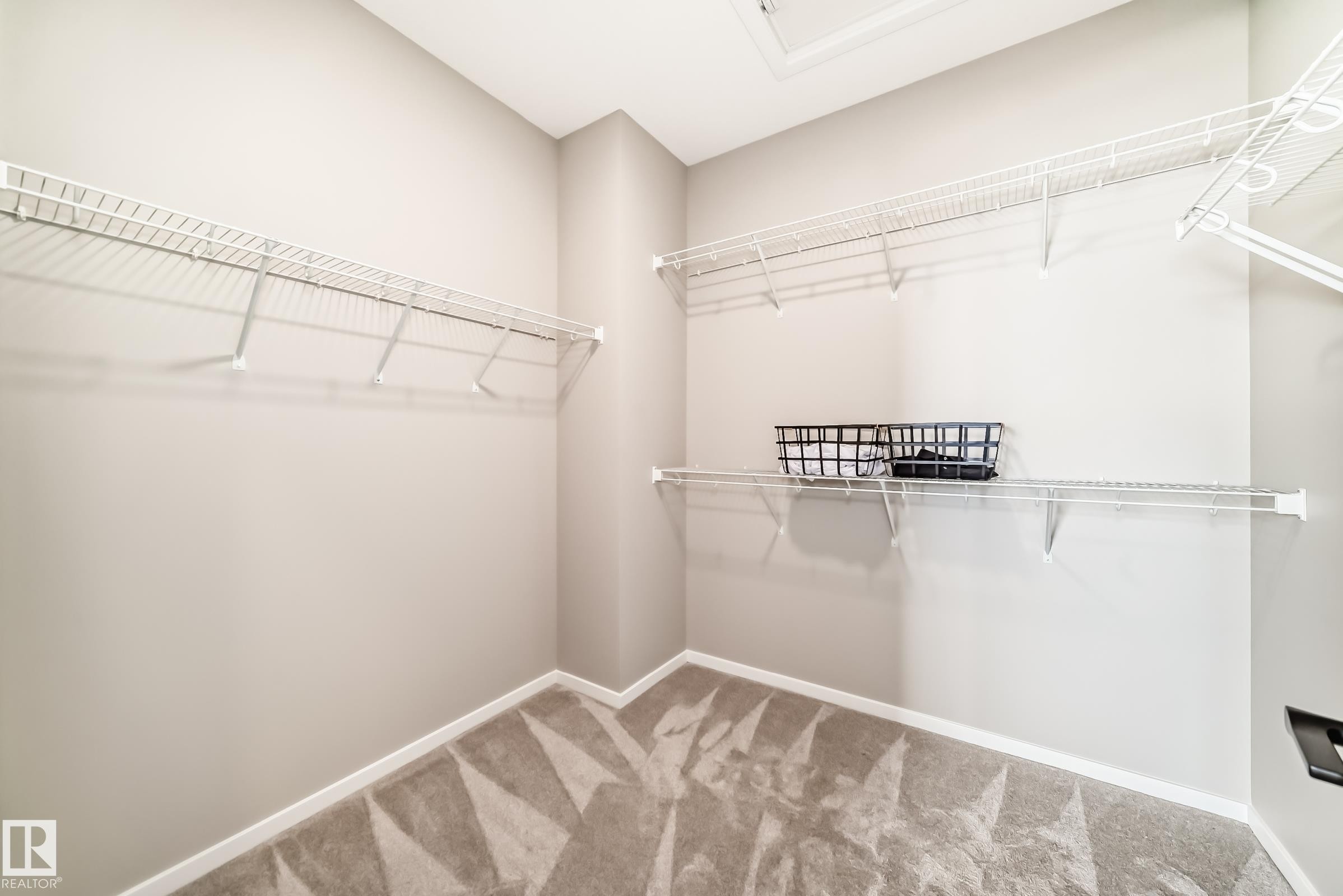 Walk-in closet featuring wire shelving, white baseboards, light neutral wall paint, and a patterned carpet - 1603 206 Street, Edmonton, AB - Indoor With Storage