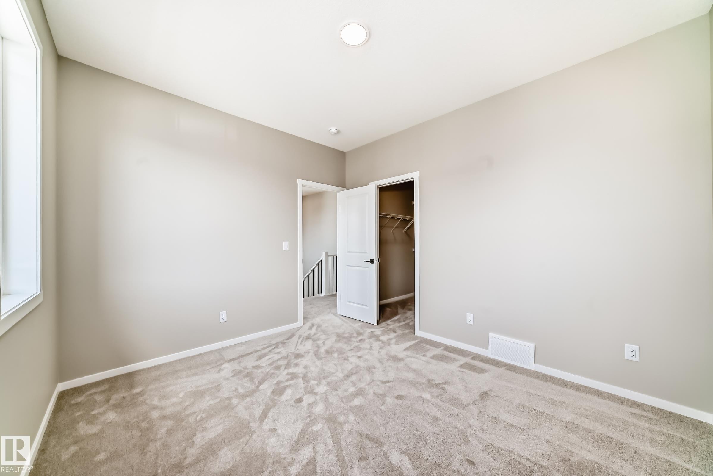Carpeted interior room featuring light gray walls, a window with white trim, and a white interior door - 1603 206 Street, Edmonton, AB - Indoor Photo Showing Other Room