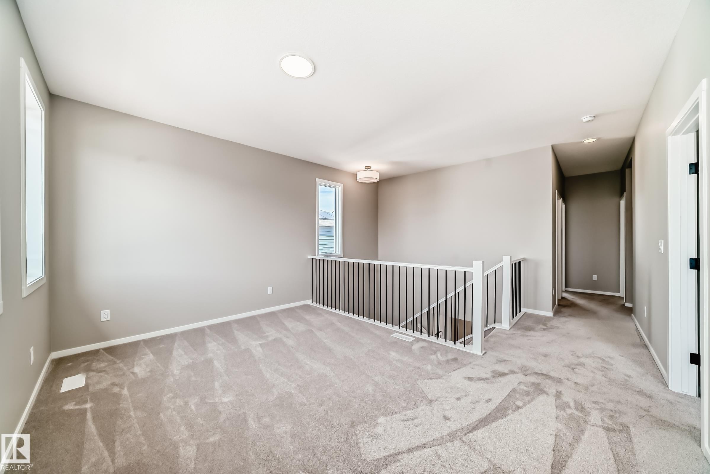 Carpeted loft area featuring a white spindle railing and contemporary wall sconce lighting - 1603 206 Street, Edmonton, AB - Indoor Photo Showing Other Room