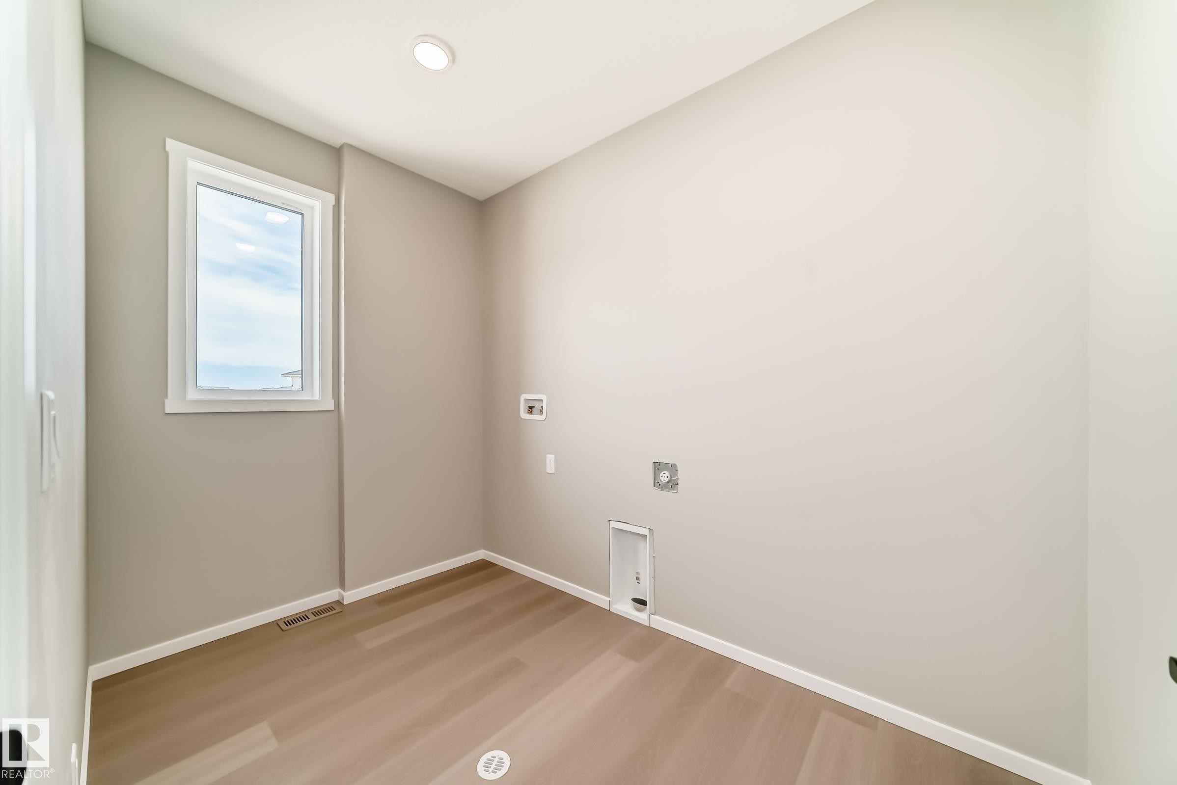 Laundry room with wood-finish flooring, recessed lighting, and a white-framed window - 1603 206 Street, Edmonton, AB - Indoor Photo Showing Other Room