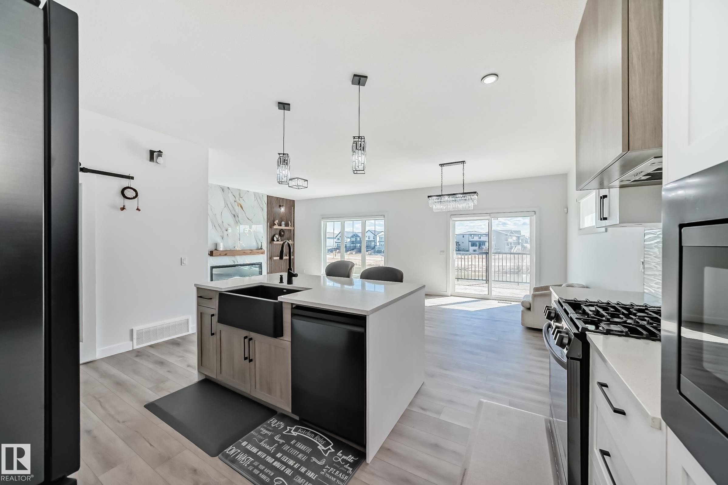 Modern kitchen island featuring a farmhouse sink, integrated dishwasher, and pendant lighting - 3247 Chernowski Way, Edmonton, AB - Indoor Photo Showing Kitchen With Stainless Steel Kitchen With Upgraded Kitchen