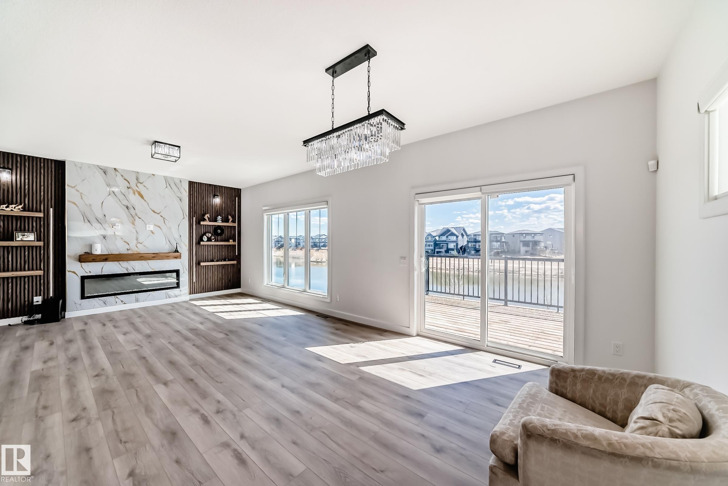 Spacious interior featuring wide plank wood-finish flooring and a contemporary fireplace with a stone-look surround and wood mantle - 3247 Chernowski Way, Edmonton, AB - Indoor