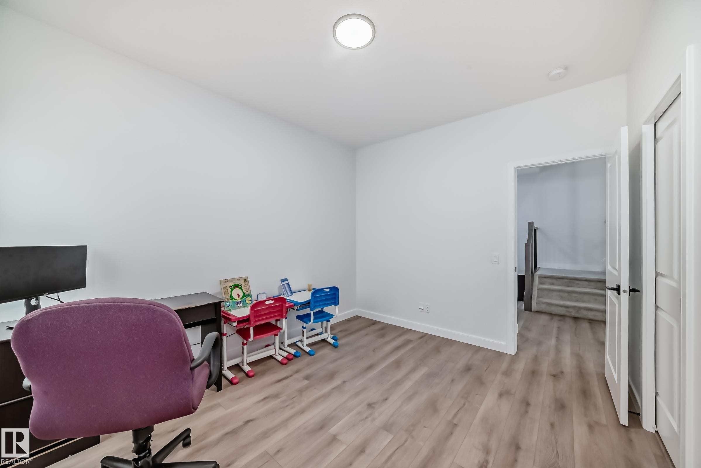 Spacious room featuring wood-finish flooring, white walls, and a ceiling-mounted light fixture - 3247 Chernowski Way, Edmonton, AB - Indoor Photo Showing Office