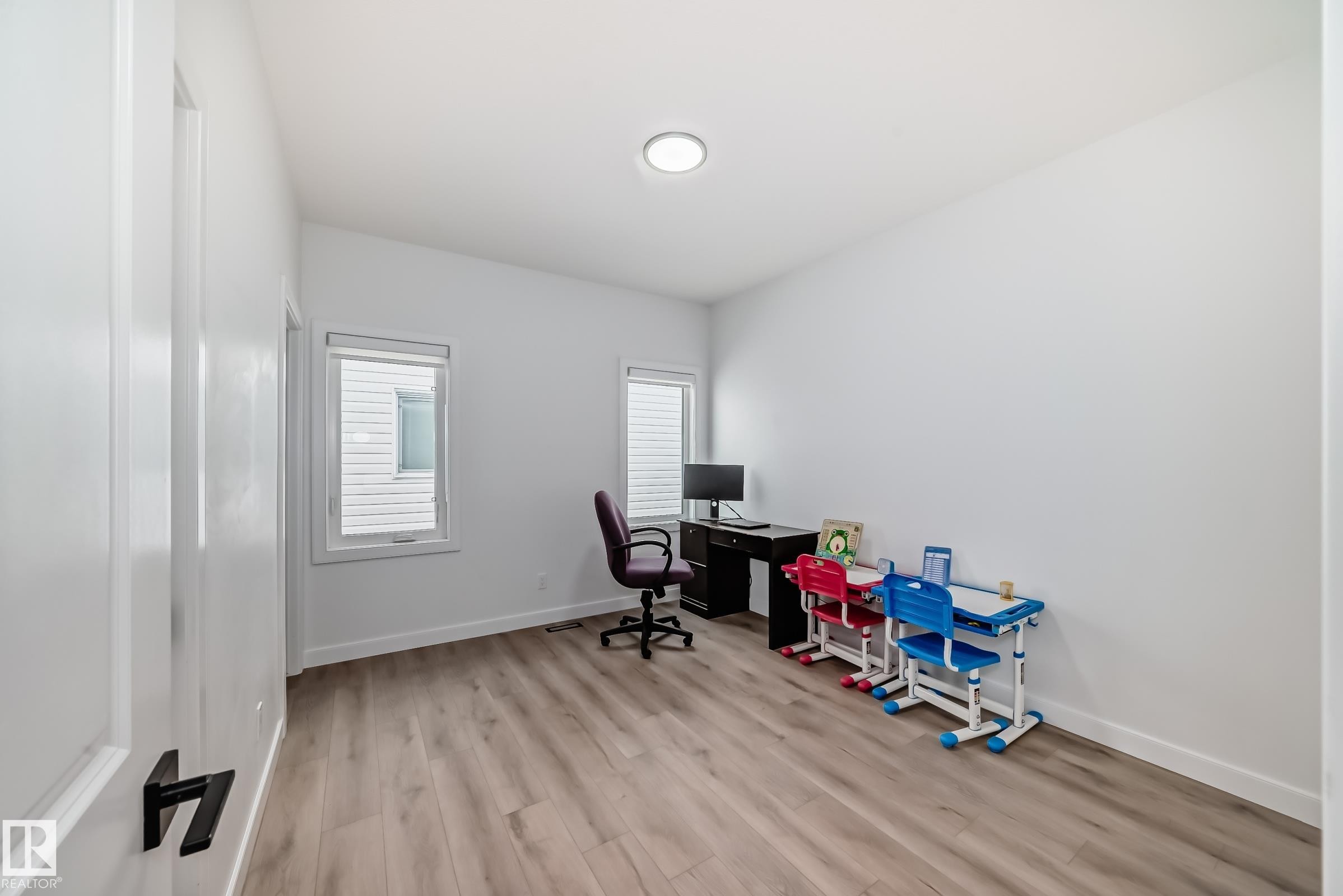 Bright room with light wood-finish flooring, white walls, and two windows with horizontal blinds - 3247 Chernowski Way, Edmonton, AB - Indoor Photo Showing Office