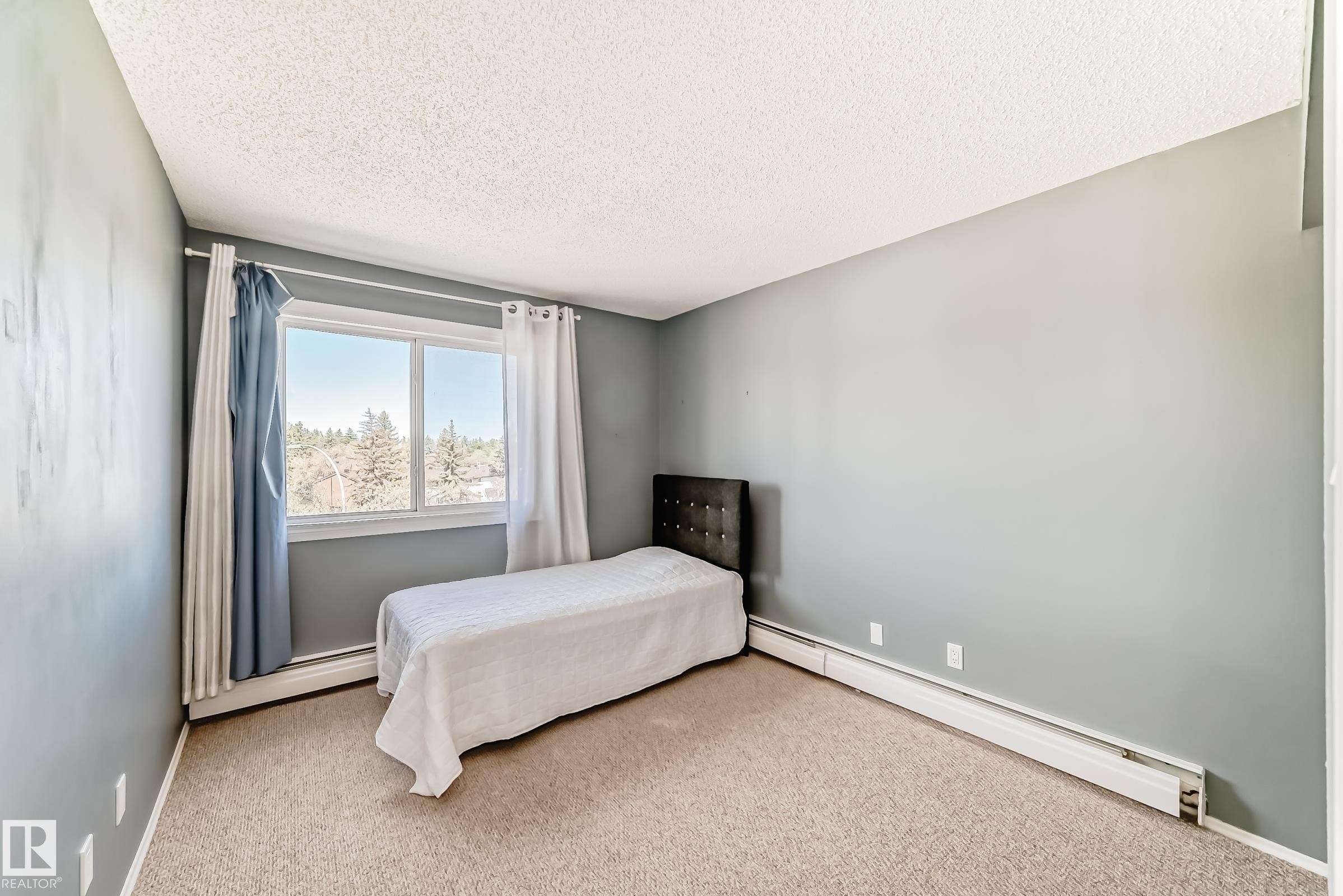 Carpeted room with a large window and baseboard heating - 423 5125 Riverbend Road, Edmonton, AB - Indoor Photo Showing Bedroom