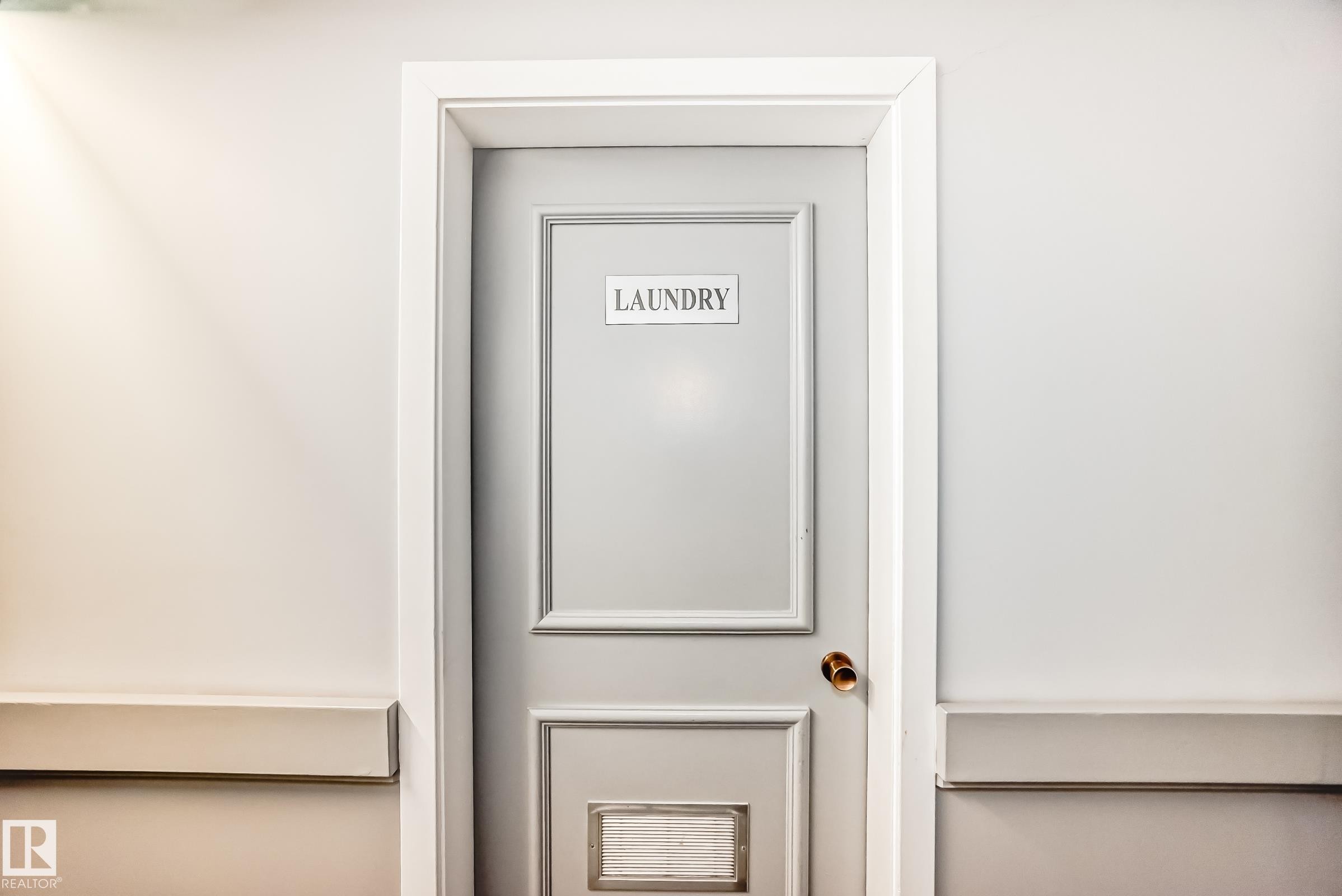 Laundry room entrance with a paneled door, brass hardware, and white trim - 423 5125 Riverbend Road, Edmonton, AB - Indoor Photo Showing Other Room