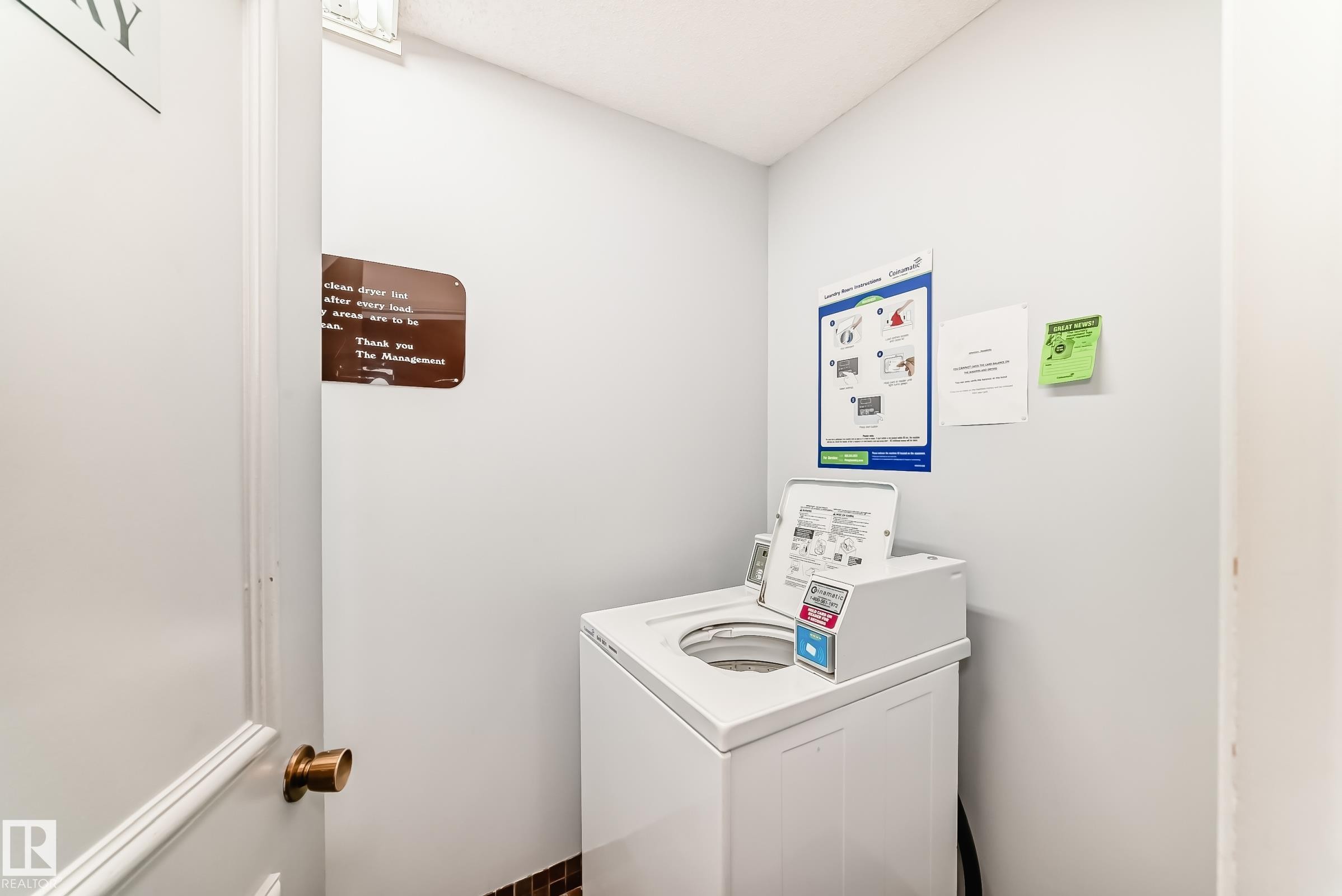 Dedicated laundry area featuring a top-loading washer, light gray wall paint, and a dark tile base - 423 5125 Riverbend Road, Edmonton, AB - Indoor Photo Showing Laundry Room