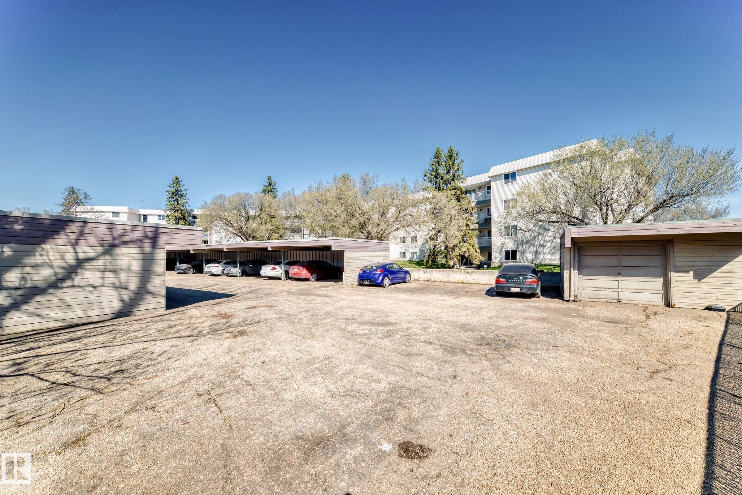 Surface parking area featuring covered stalls and individual garage units - 423 5125 Riverbend Road, Edmonton, AB - Outdoor