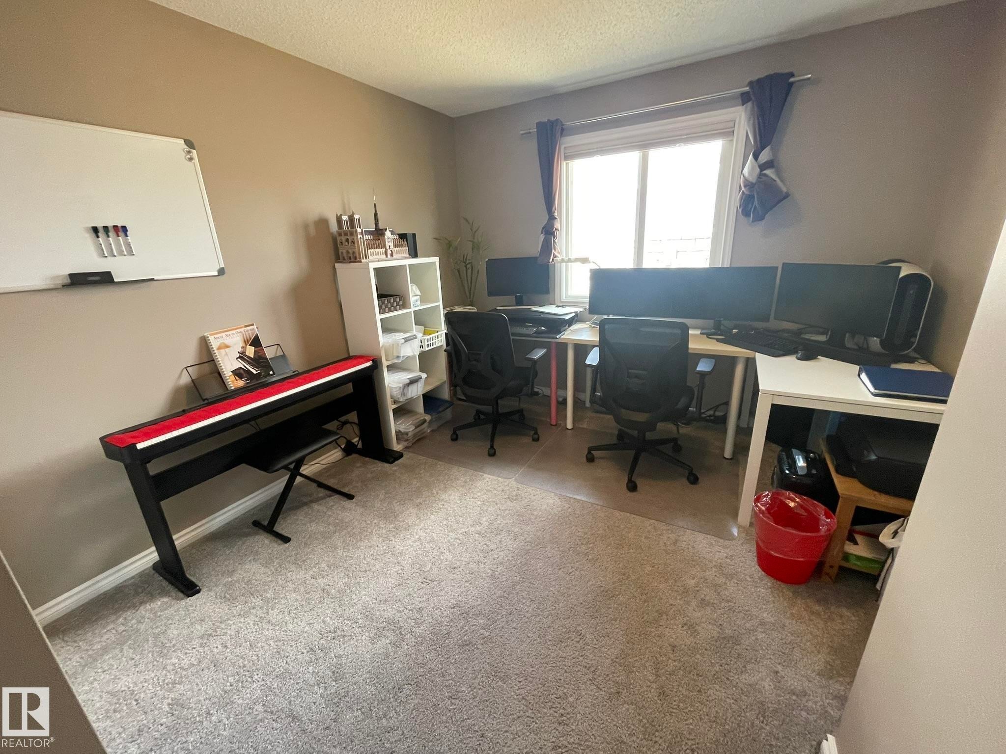 Carpeted room featuring a white board, built-in shelving, two desks, and a window with white trim - 871 Ebbers Crescent, Edmonton, AB - Indoor Photo Showing Office