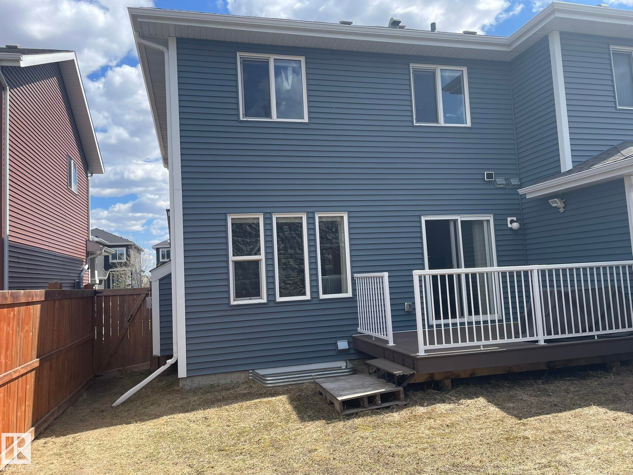Rear exterior featuring blue horizontal siding, a multi-level deck with white railings, and a sliding glass door - 871 Ebbers Crescent, Edmonton, AB - Outdoor With Deck Patio Veranda With Exterior