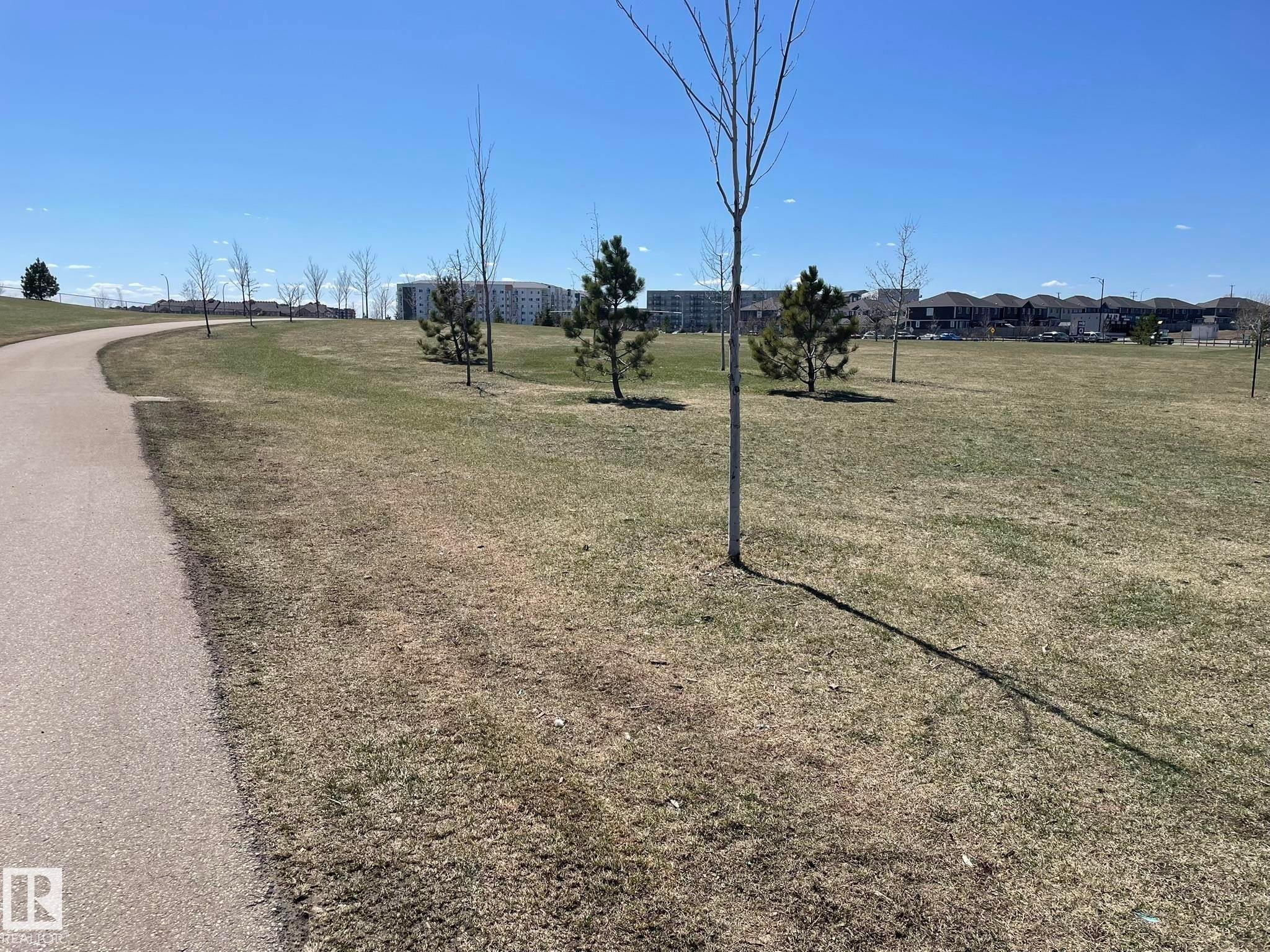 Curved paved pathway bordering an expansive green space with scattered trees - 871 Ebbers Crescent, Edmonton, AB - Outdoor With View