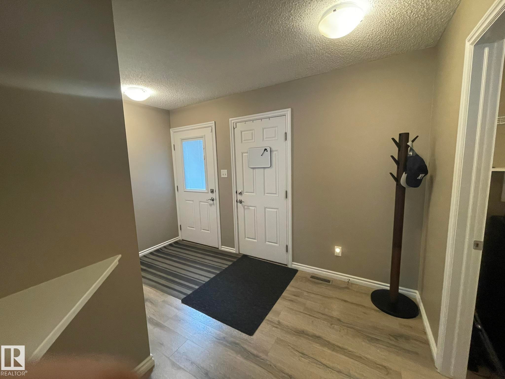 Entryway featuring two white panel doors, wood-finish flooring, and neutral wall paint - 871 Ebbers Crescent, Edmonton, AB - Indoor Photo Showing Other Room