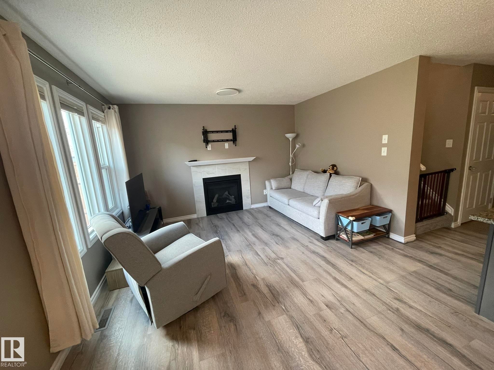 Living space featuring wood-finish flooring and neutral wall tones - 871 Ebbers Crescent, Edmonton, AB - Indoor Photo Showing Living Room With Fireplace