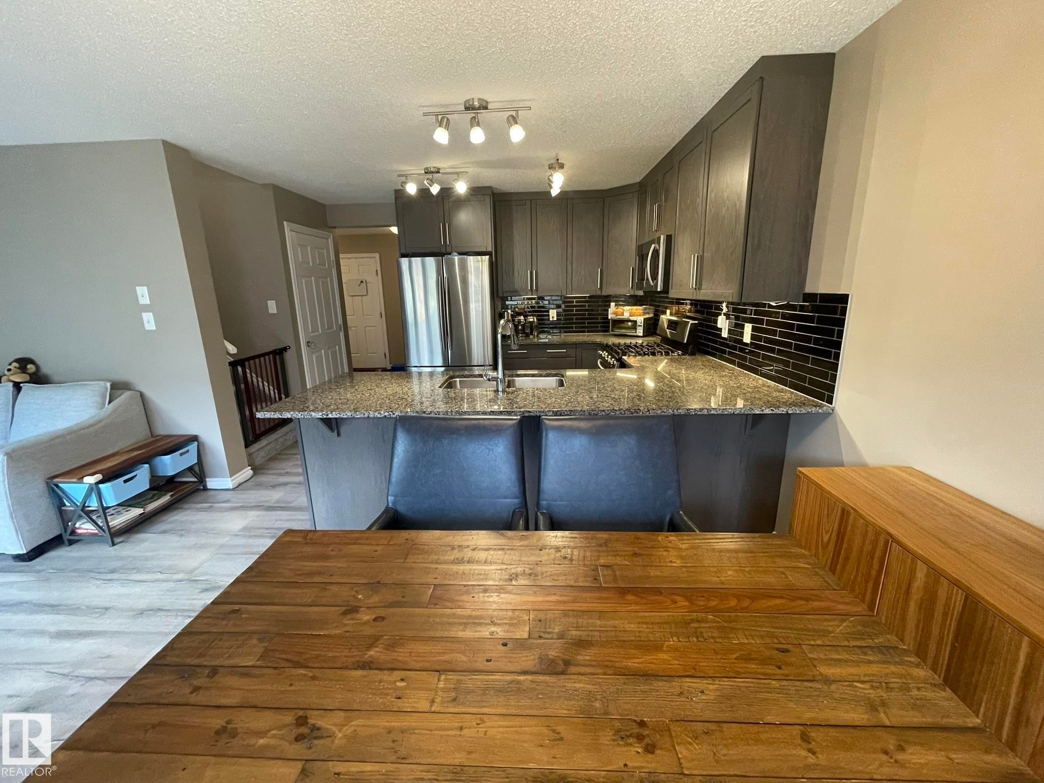 Modern kitchen featuring stainless steel appliances, dark cabinetry, and a granite-look countertop - 871 Ebbers Crescent, Edmonton, AB - Indoor Photo Showing Kitchen With Upgraded Kitchen
