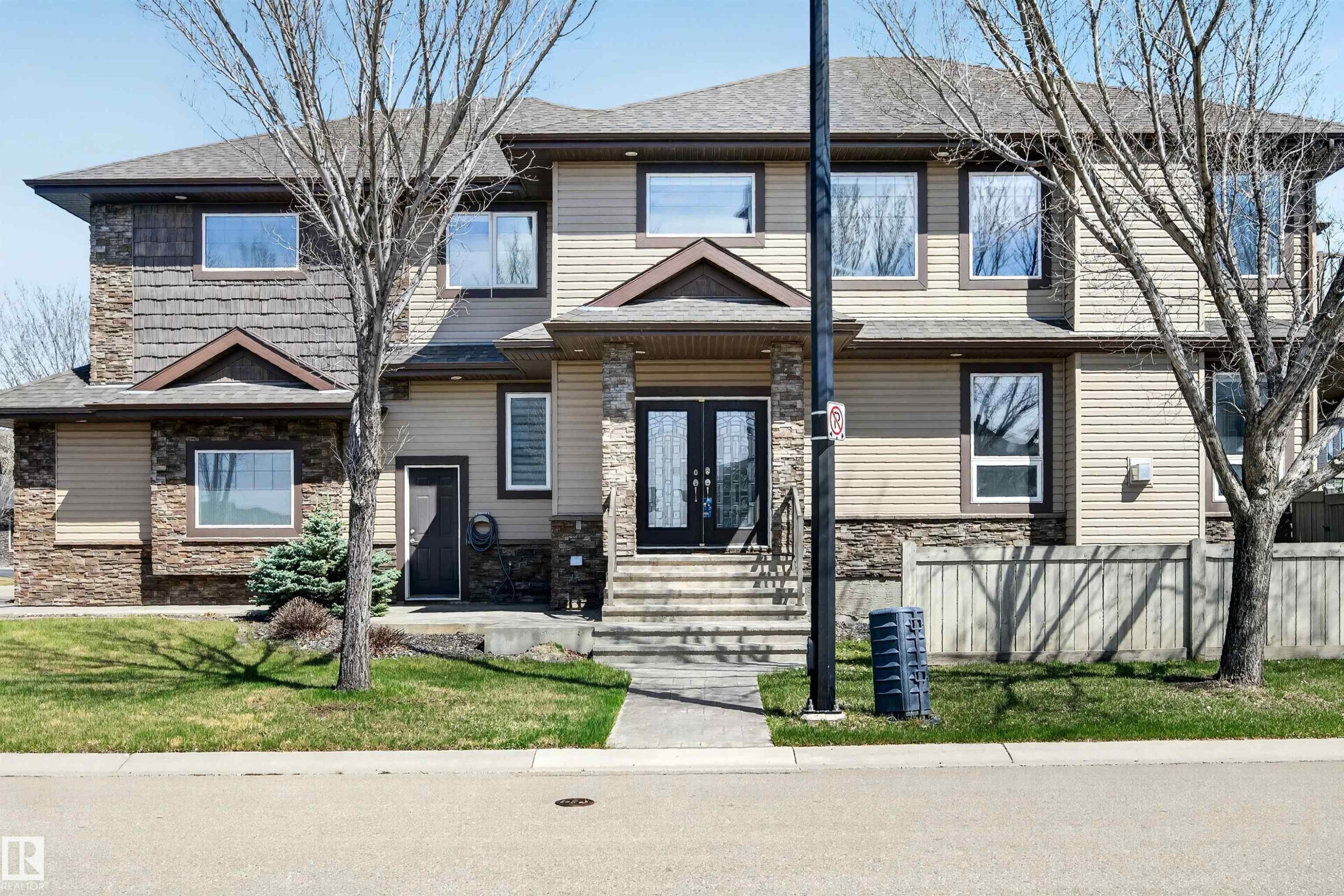 Multi-level residence featuring a stone and siding exterior, prominent front entry with double doors, and a concrete walkway - 1254 Adamson Drive, Edmonton, AB - Outdoor With Facade