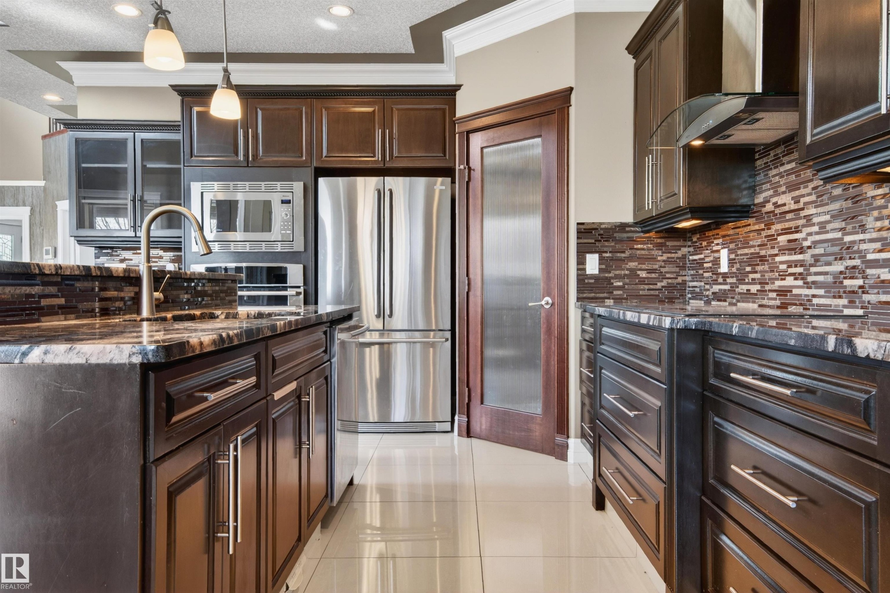 Kitchen featuring dark wood cabinetry, stainless steel appliances, patterned stone countertops, and a tiled backsplash - 1254 Adamson Drive, Edmonton, AB - Indoor Photo Showing Kitchen With Stainless Steel Kitchen With Upgraded Kitchen
