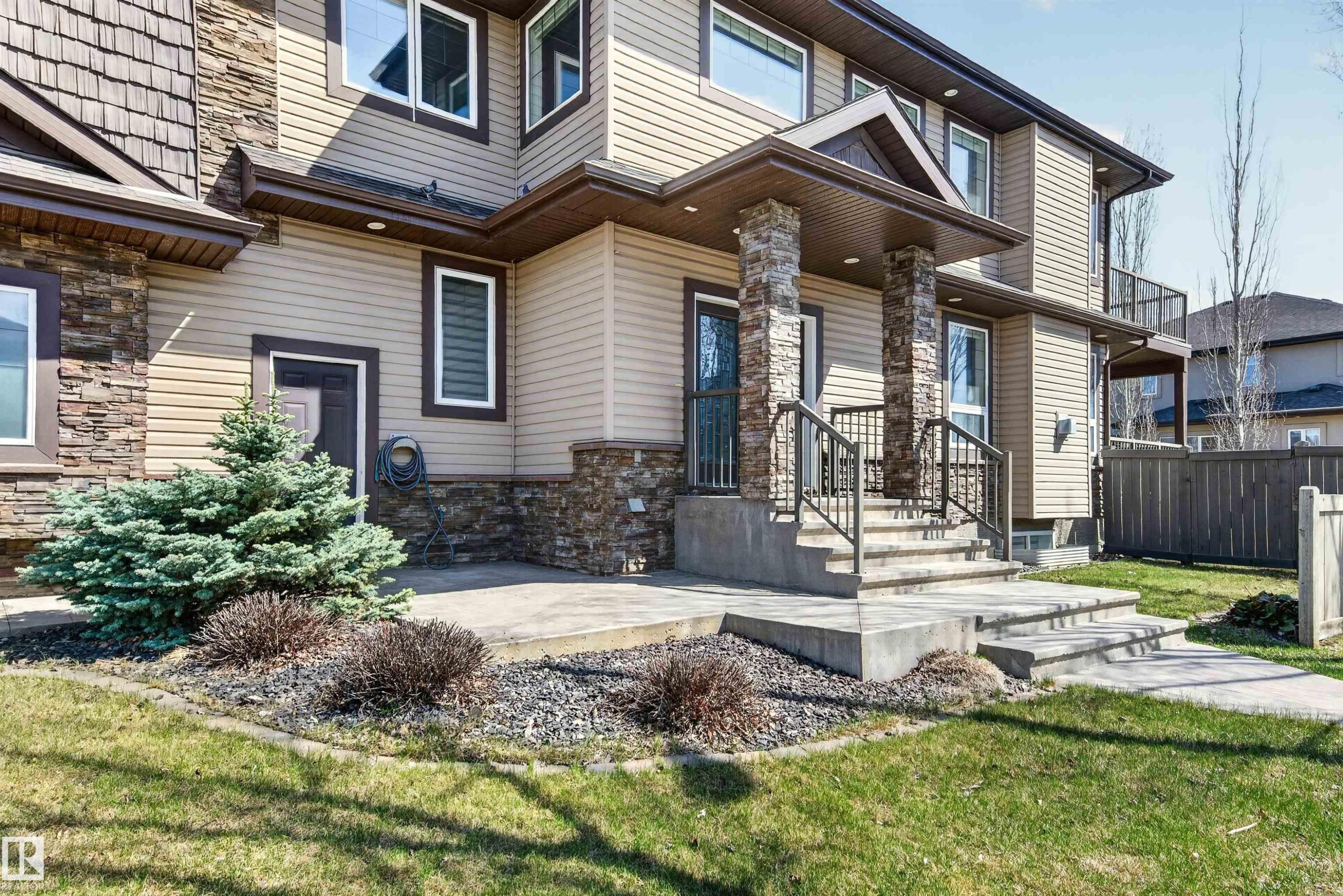 Inviting front entrance featuring stacked stone pillars, concrete steps with wrought iron railings, and a covered porch - 1254 Adamson Drive, Edmonton, AB - Outdoor
