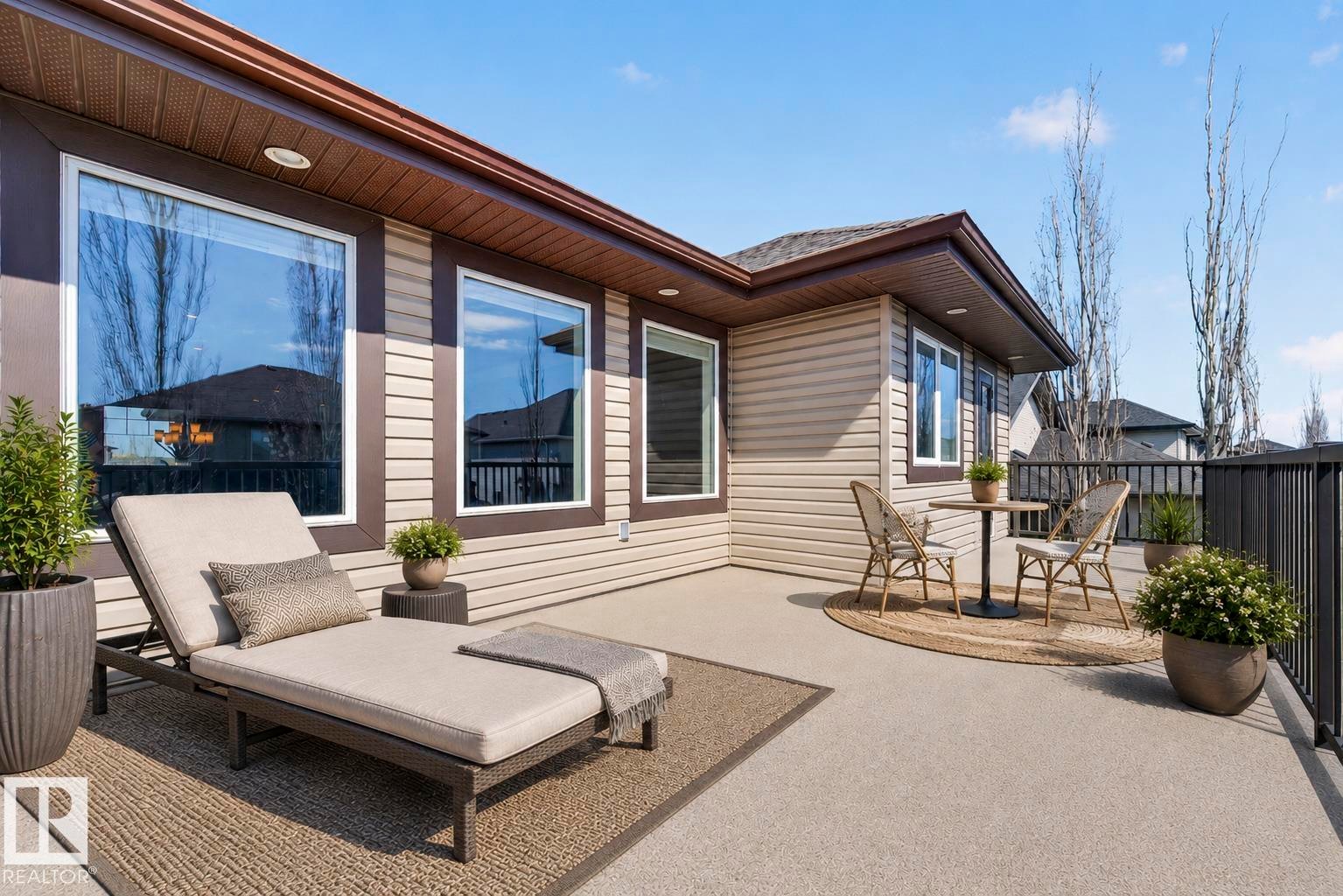 Expansive outdoor deck featuring a concrete surface, black metal railing, and brown siding exterior - 1254 Adamson Drive, Edmonton, AB - Outdoor With Deck Patio Veranda
