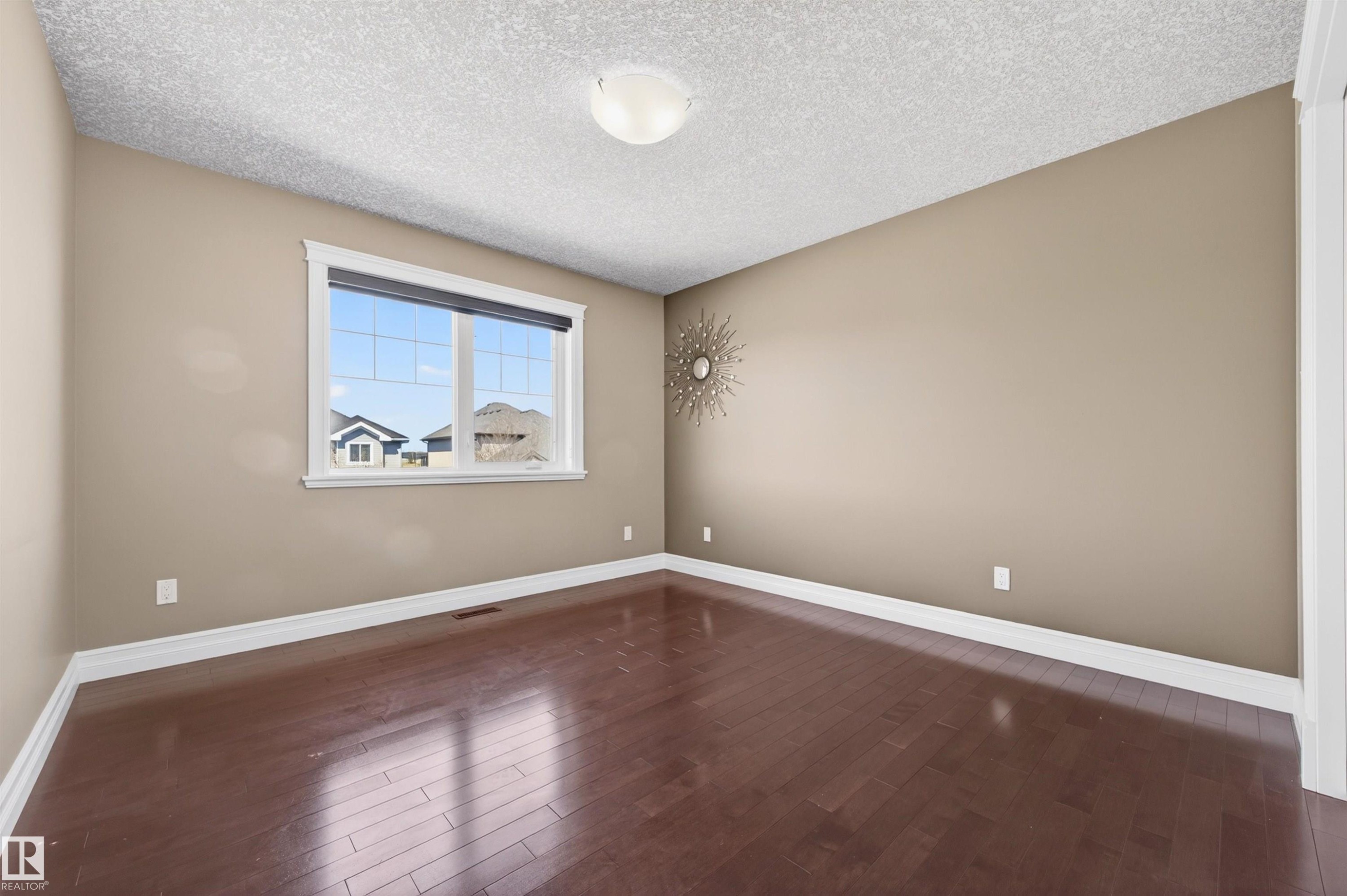 Spacious room with dark wood-finish flooring, neutral wall color, and white baseboards - 1254 Adamson Drive, Edmonton, AB - Indoor Photo Showing Other Room