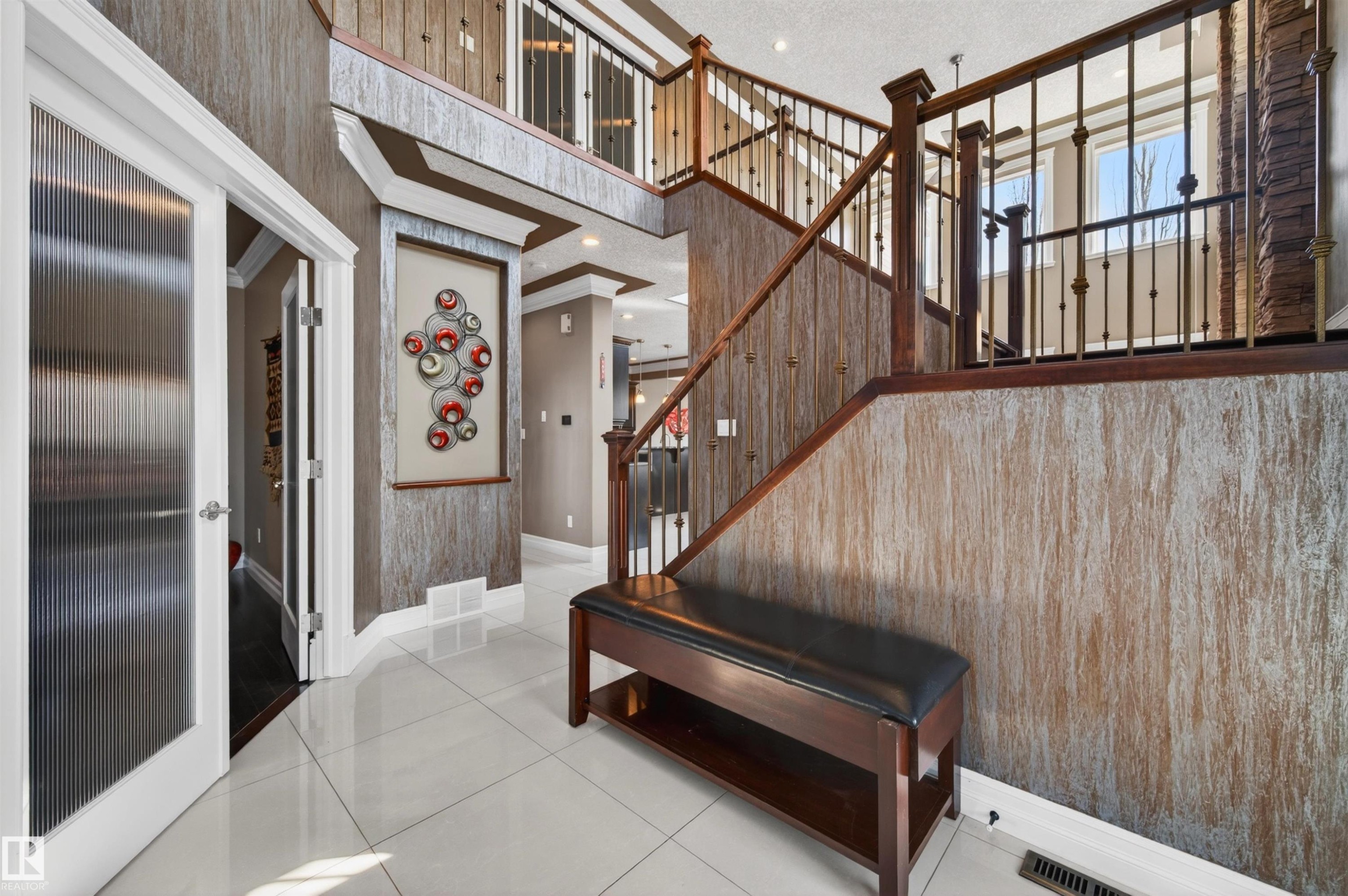 Two-story foyer featuring bright tile flooring, a dark wood-finish staircase with ornate metal balusters, textured wall finishes, and a second-story landing - 1254 Adamson Drive, Edmonton, AB - Indoor Photo Showing Other Room
