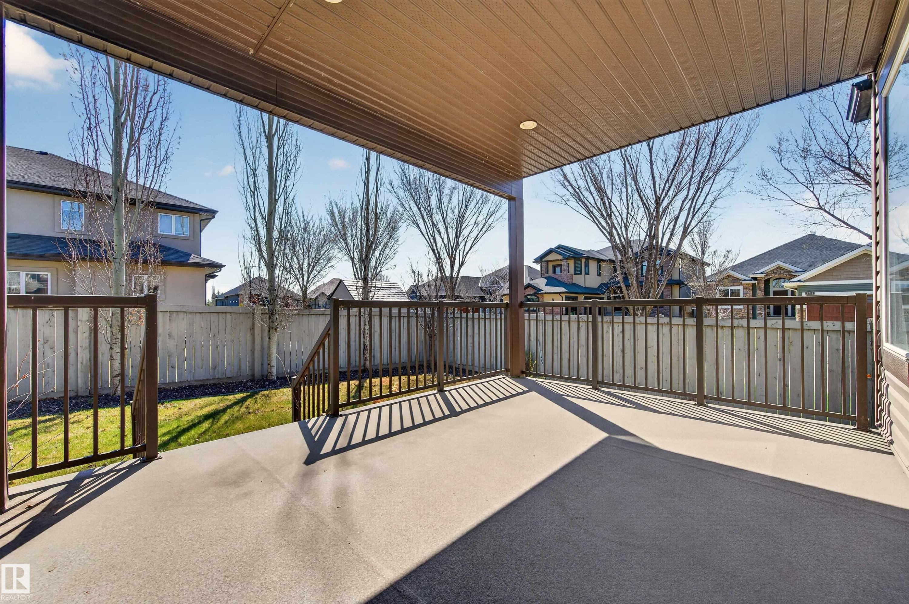 Covered concrete patio with recessed lighting, dark metal railings, and a fenced yard - 1254 Adamson Drive, Edmonton, AB - Outdoor With Deck Patio Veranda With Exterior