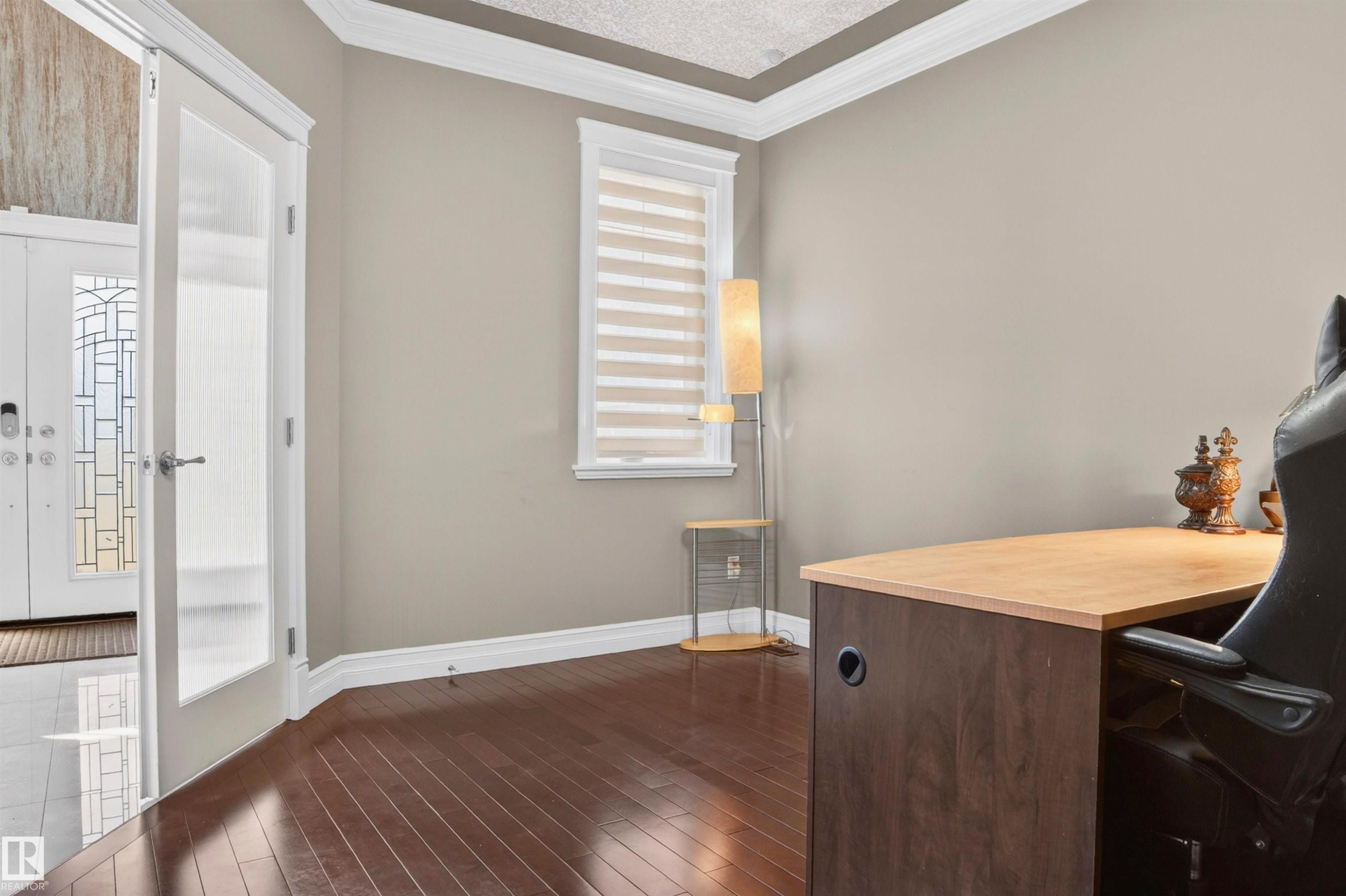 Spacious room with dark wood-finish flooring, light tan walls, and a window featuring horizontal blinds - 1254 Adamson Drive, Edmonton, AB - Indoor