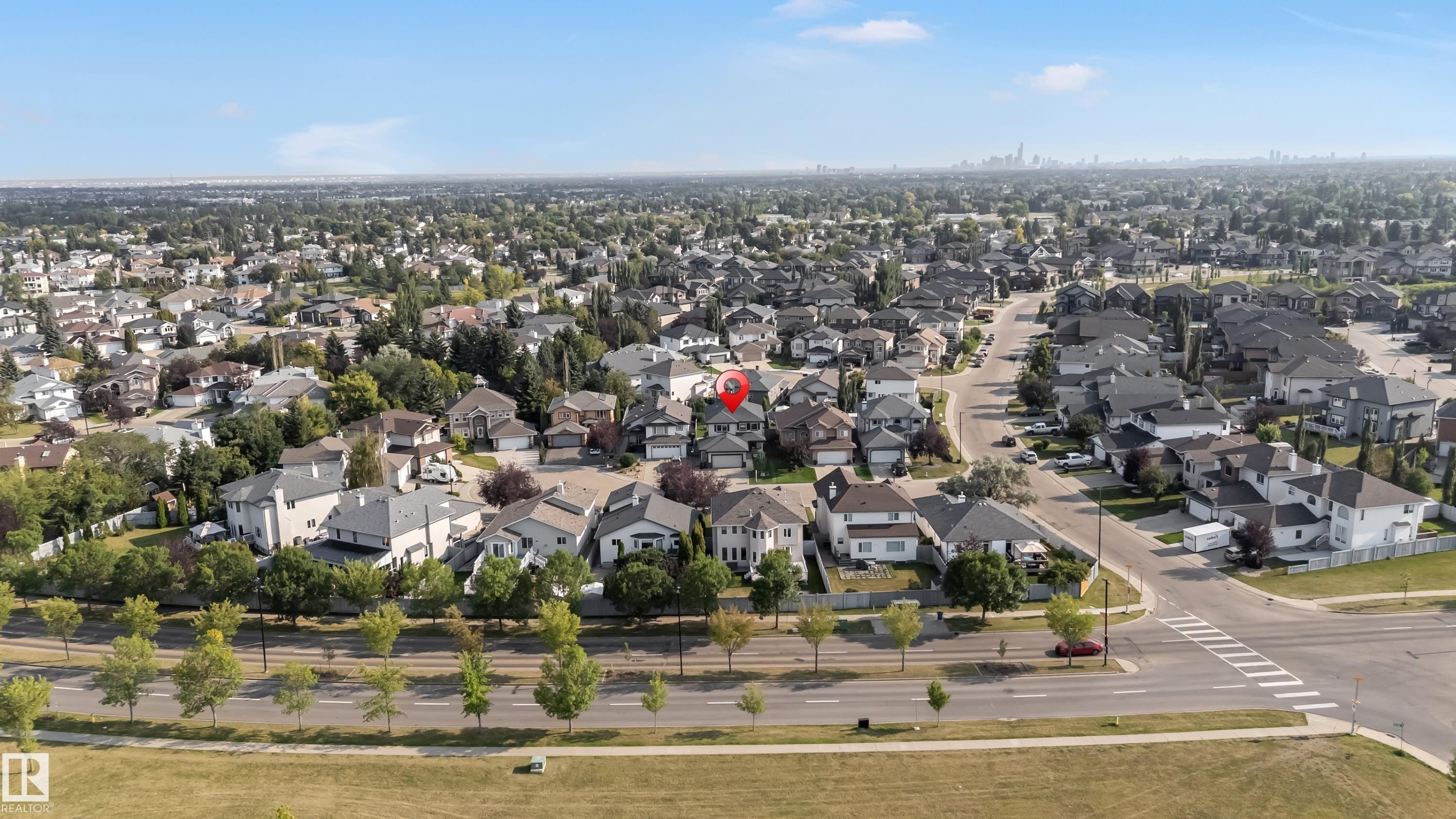 Residential neighborhood featuring a grid-pattern street layout, mature trees, and a distant city skyline - 10621 175A Avenue, Edmonton, AB