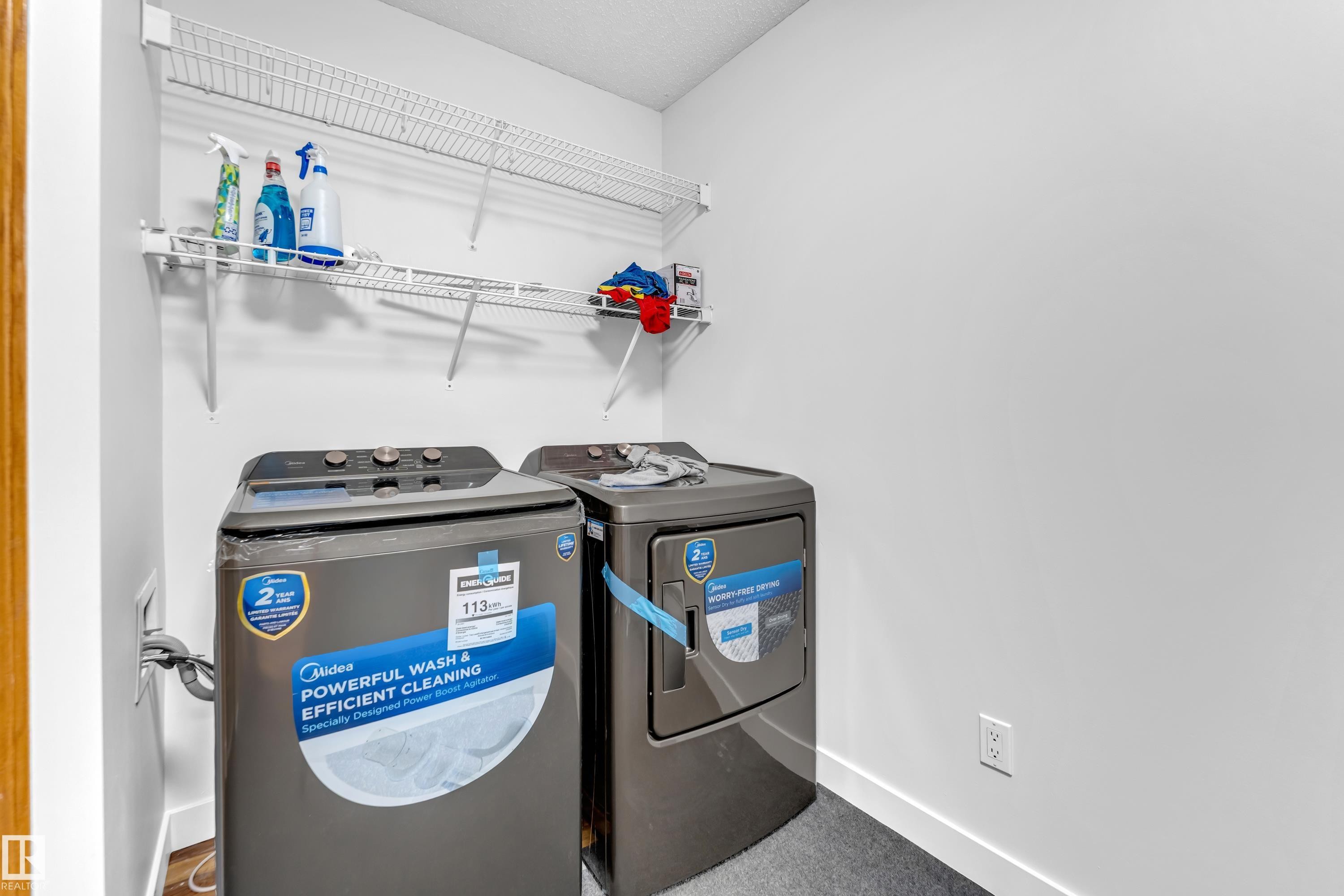Laundry area featuring a textured gray floor, white walls, and two white wire shelving units - 10621 175A Avenue, Edmonton, AB