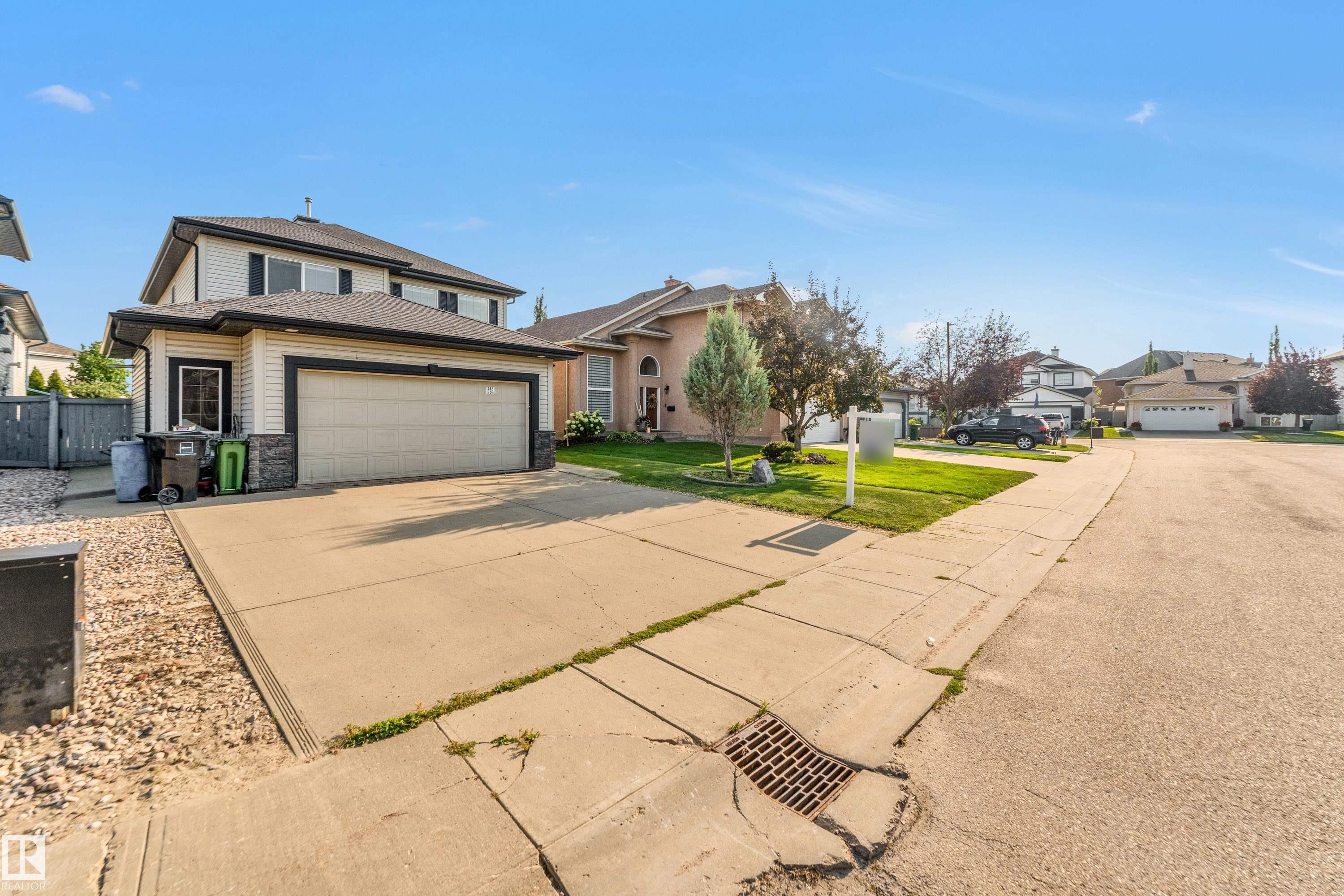 Two-story residence featuring light-colored siding with dark trim, a two-car garage, and a concrete driveway - 10621 175A Avenue, Edmonton, AB