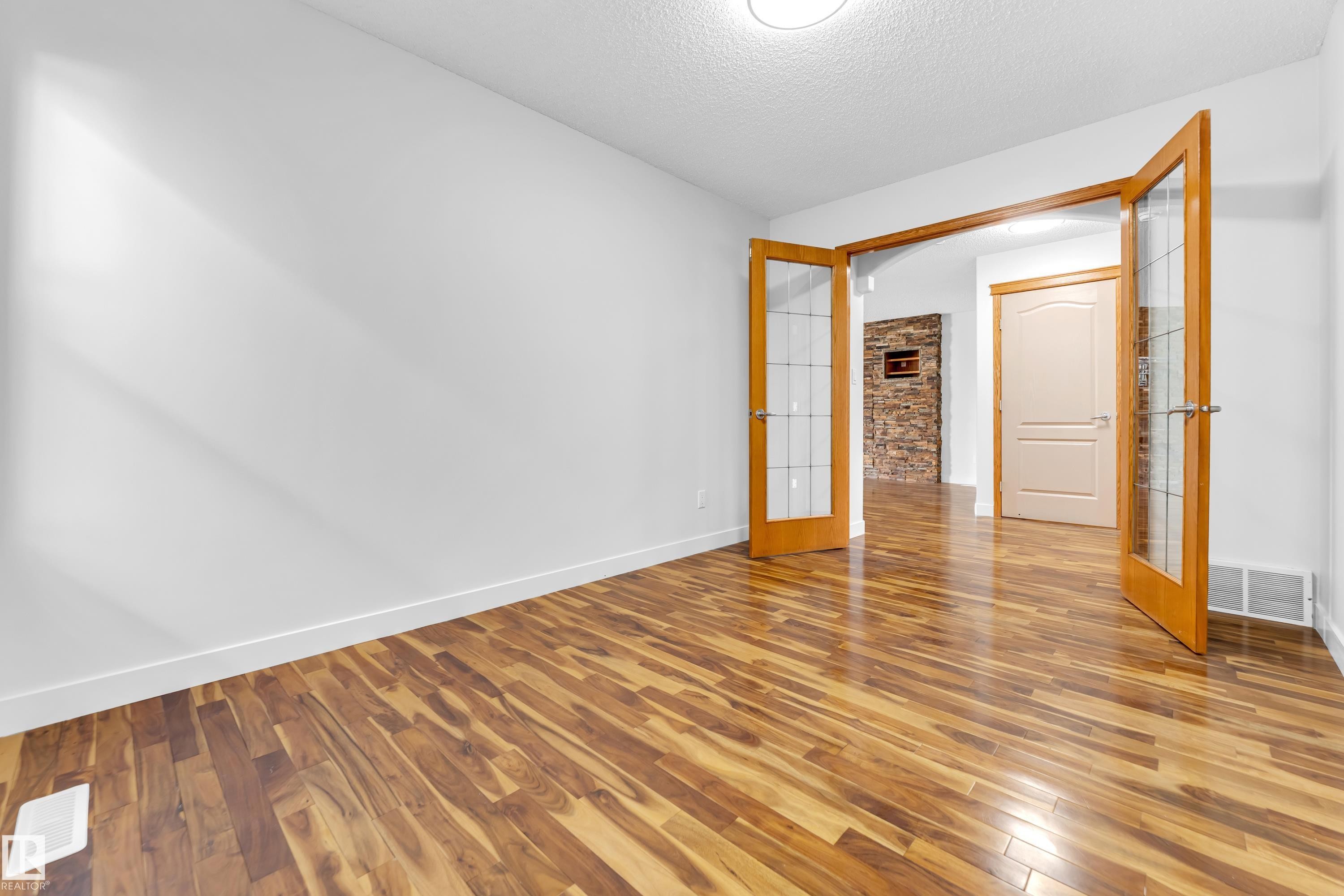 Room featuring rich wood-finish flooring, white baseboards, and a neutral wall palette - 10621 175A Avenue, Edmonton, AB