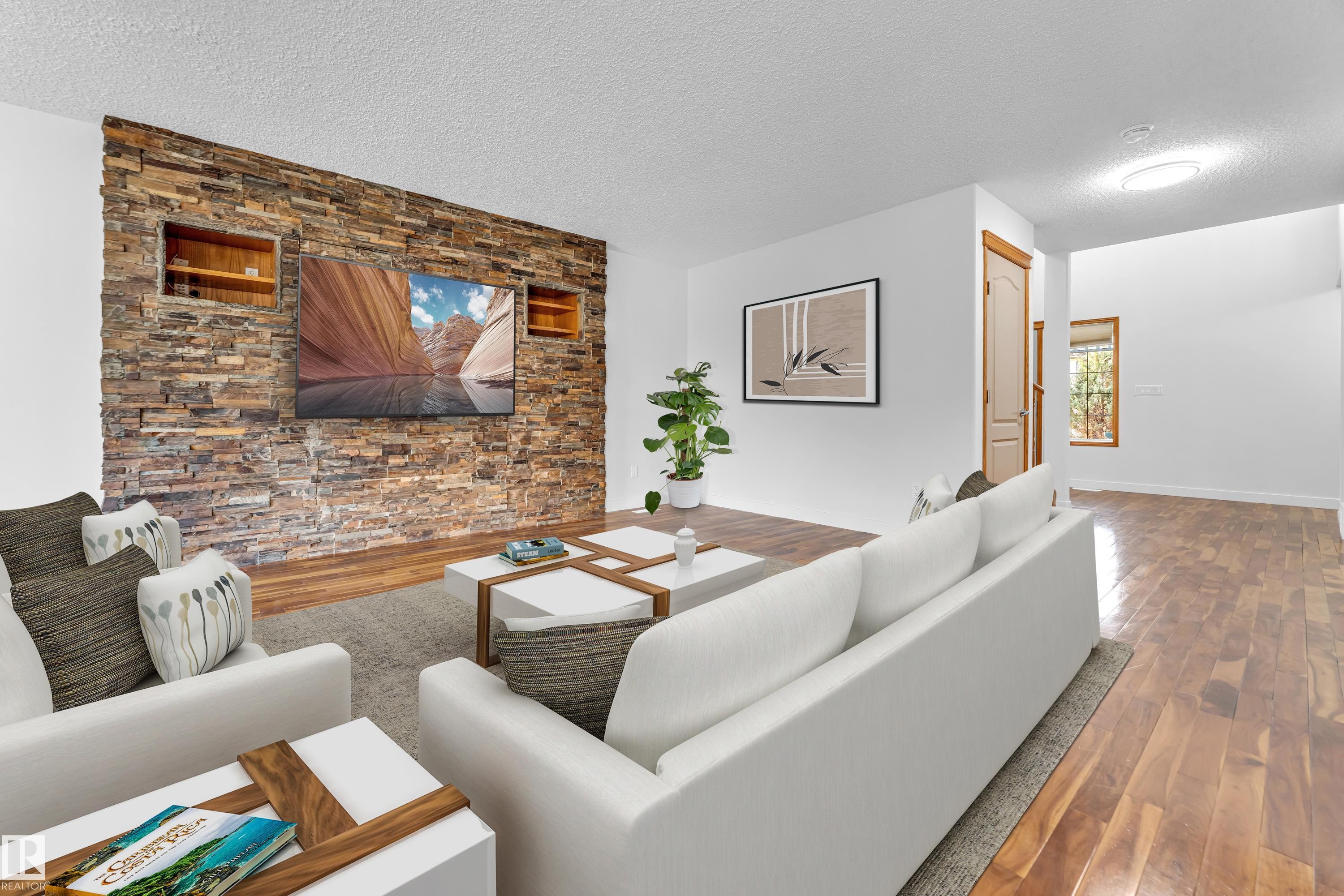 Living area featuring a stone veneer accent wall with integrated shelving, recessed lighting, wood-finish flooring, and crisp white walls - 10621 175A Avenue, Edmonton, AB
