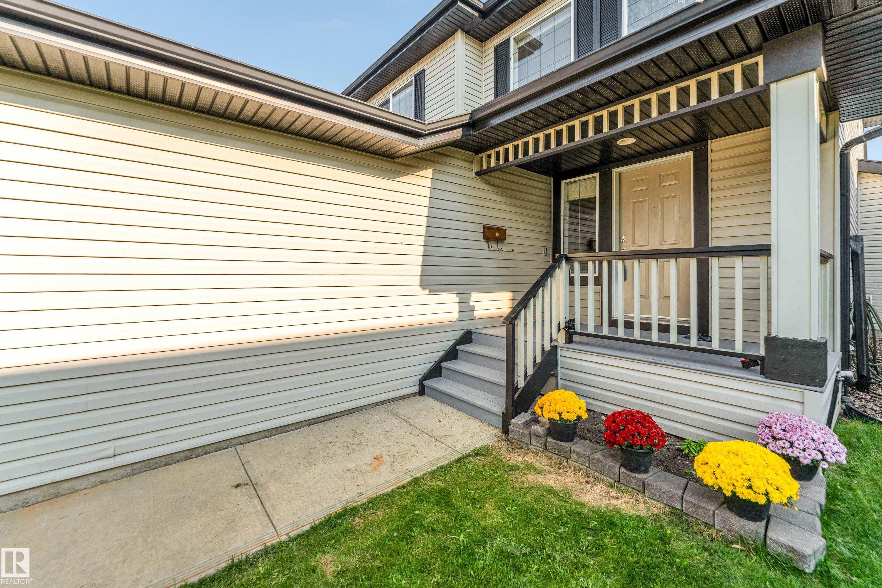 Inviting front entry featuring a covered porch, white paneled door, and dark trim - 10621 175A Avenue, Edmonton, AB