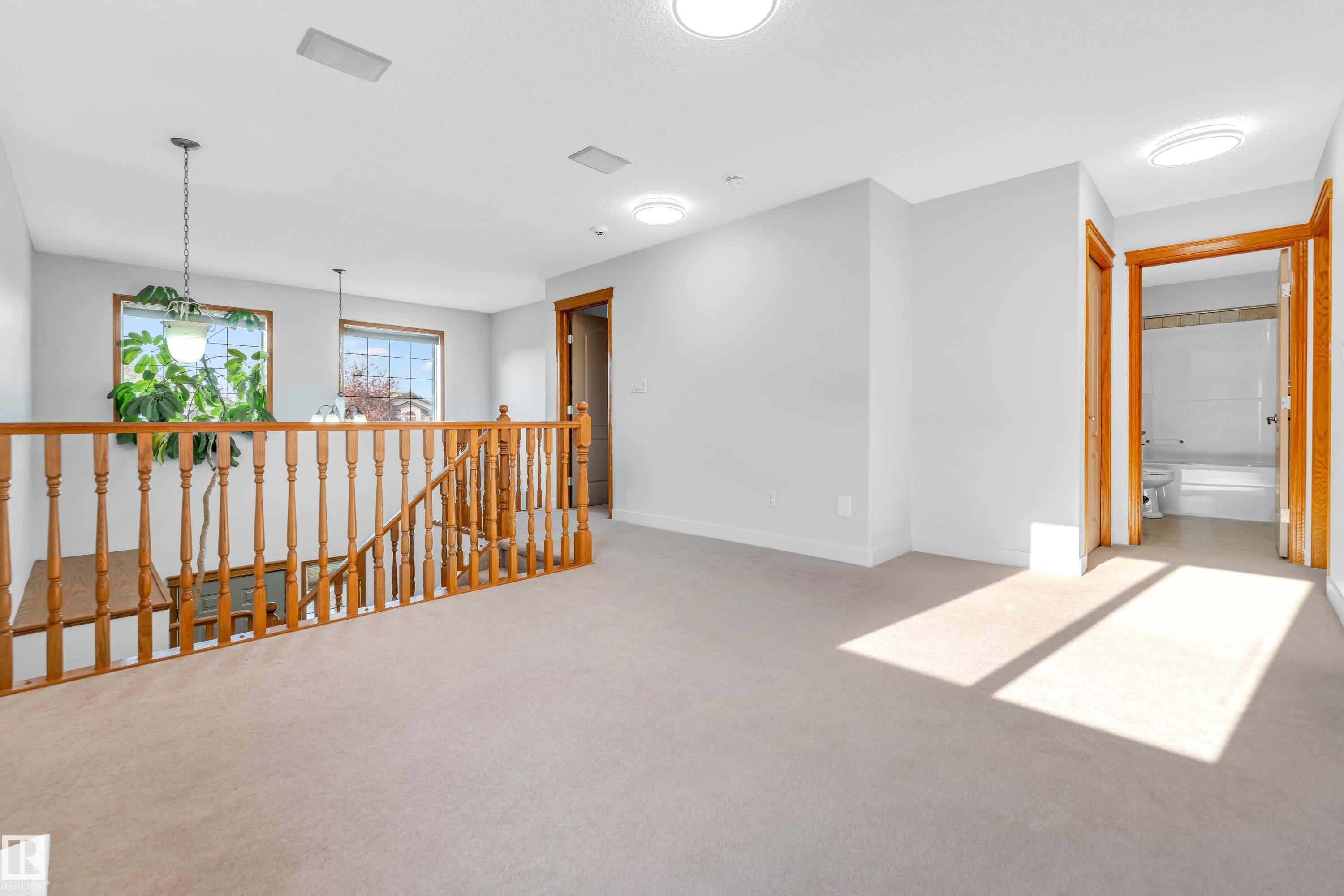 Upper-level landing featuring light-toned carpet, recessed lighting, and a wooden baluster railing - 10621 175A Avenue, Edmonton, AB