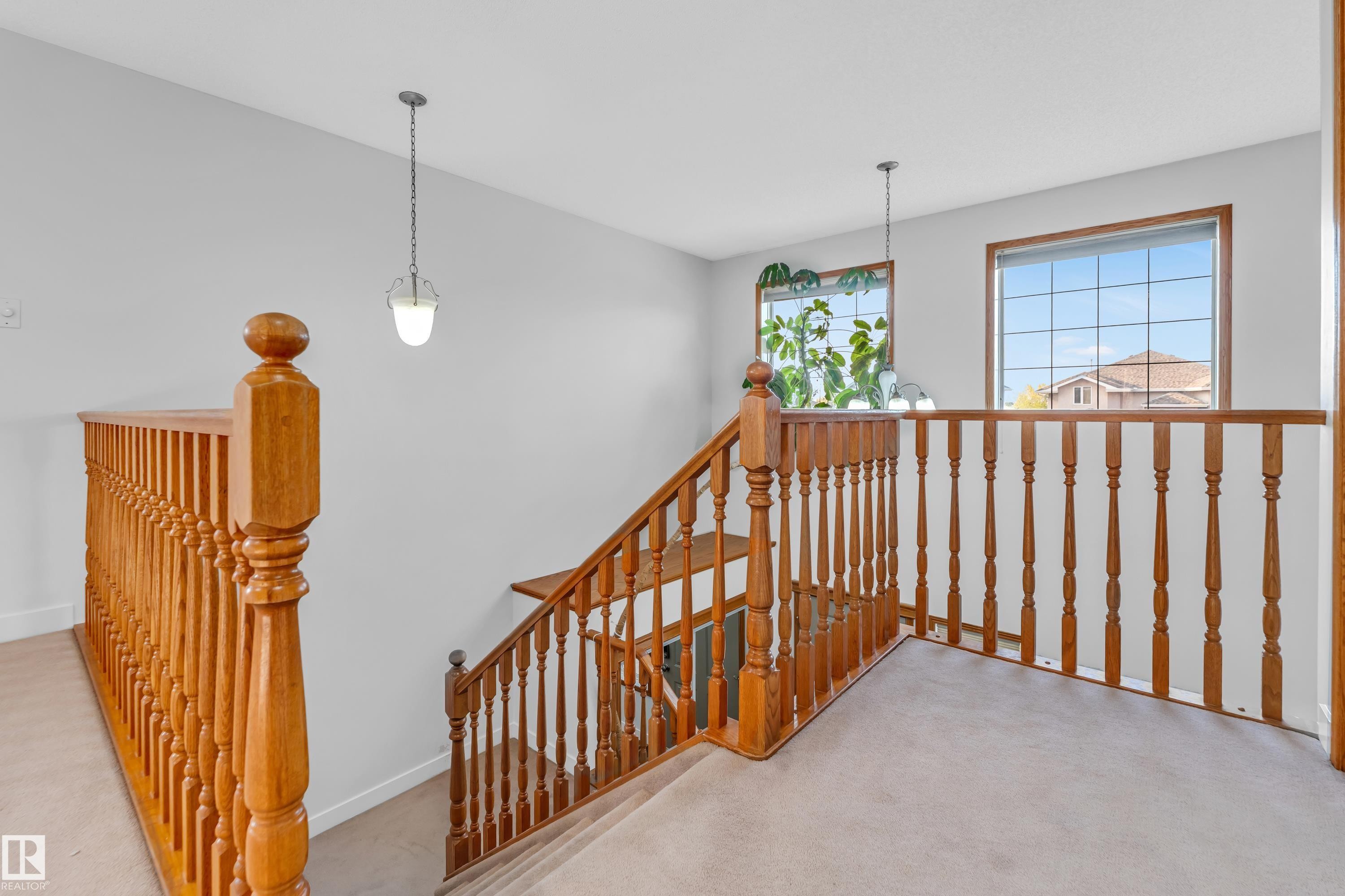 Upper-level landing featuring wood balusters and two pendant light fixtures - 10621 175A Avenue, Edmonton, AB