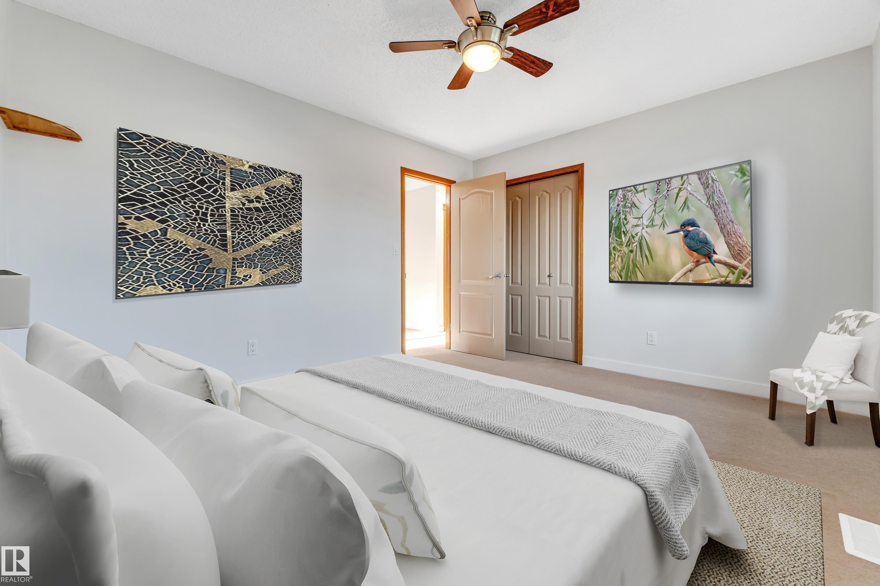 Carpeted bedroom featuring light-toned walls, a brown paneled door, a bi-fold closet door, and a ceiling fan with integrated lighting - 10621 175A Avenue, Edmonton, AB