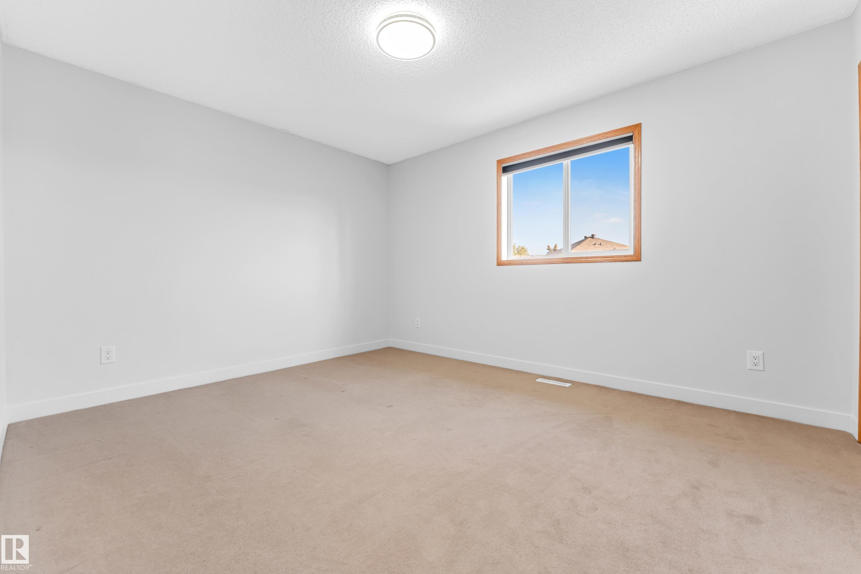 Bright room featuring neutral carpeting, white walls, and a window with wood-finish trim - 10621 175A Avenue, Edmonton, AB