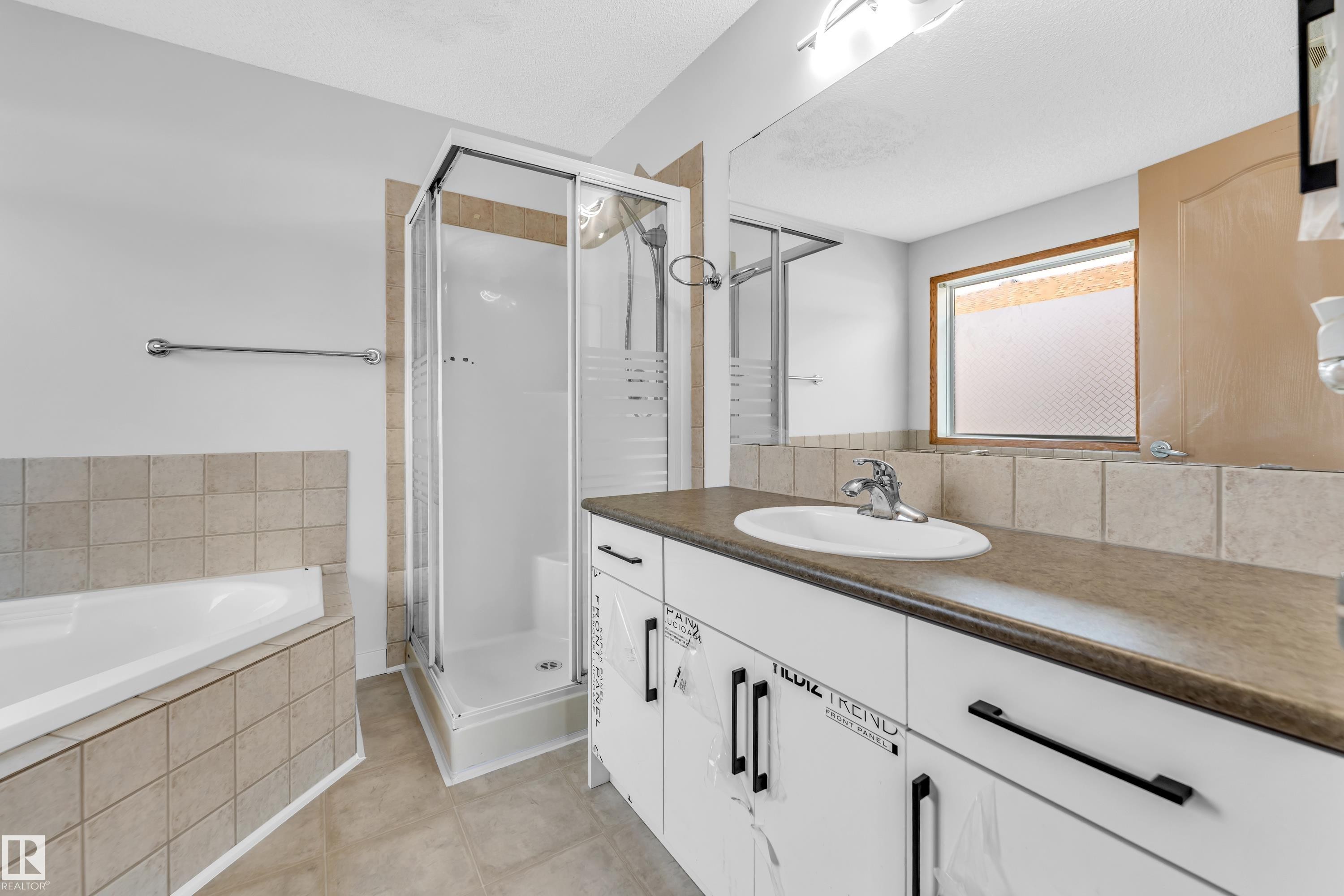 Bathroom featuring a white vanity with dark countertop, an integrated sink, and an expansive mirror - 10621 175A Avenue, Edmonton, AB