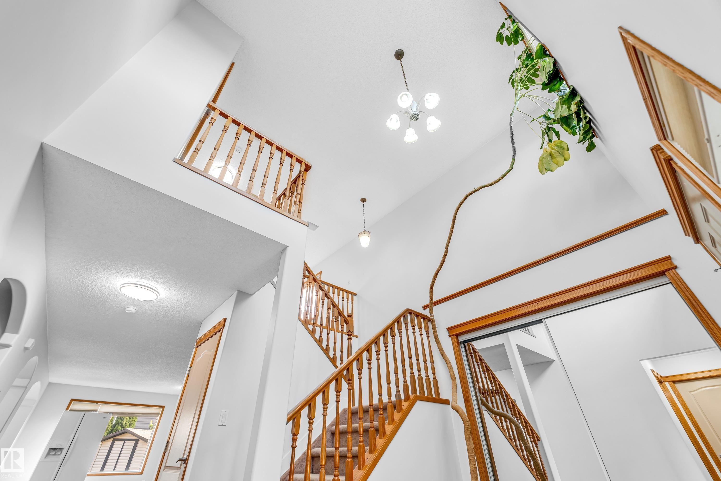 Multi-level foyer featuring soaring ceilings, a wood staircase with spindle balusters, and a recessed ceiling light - 10621 175A Avenue, Edmonton, AB