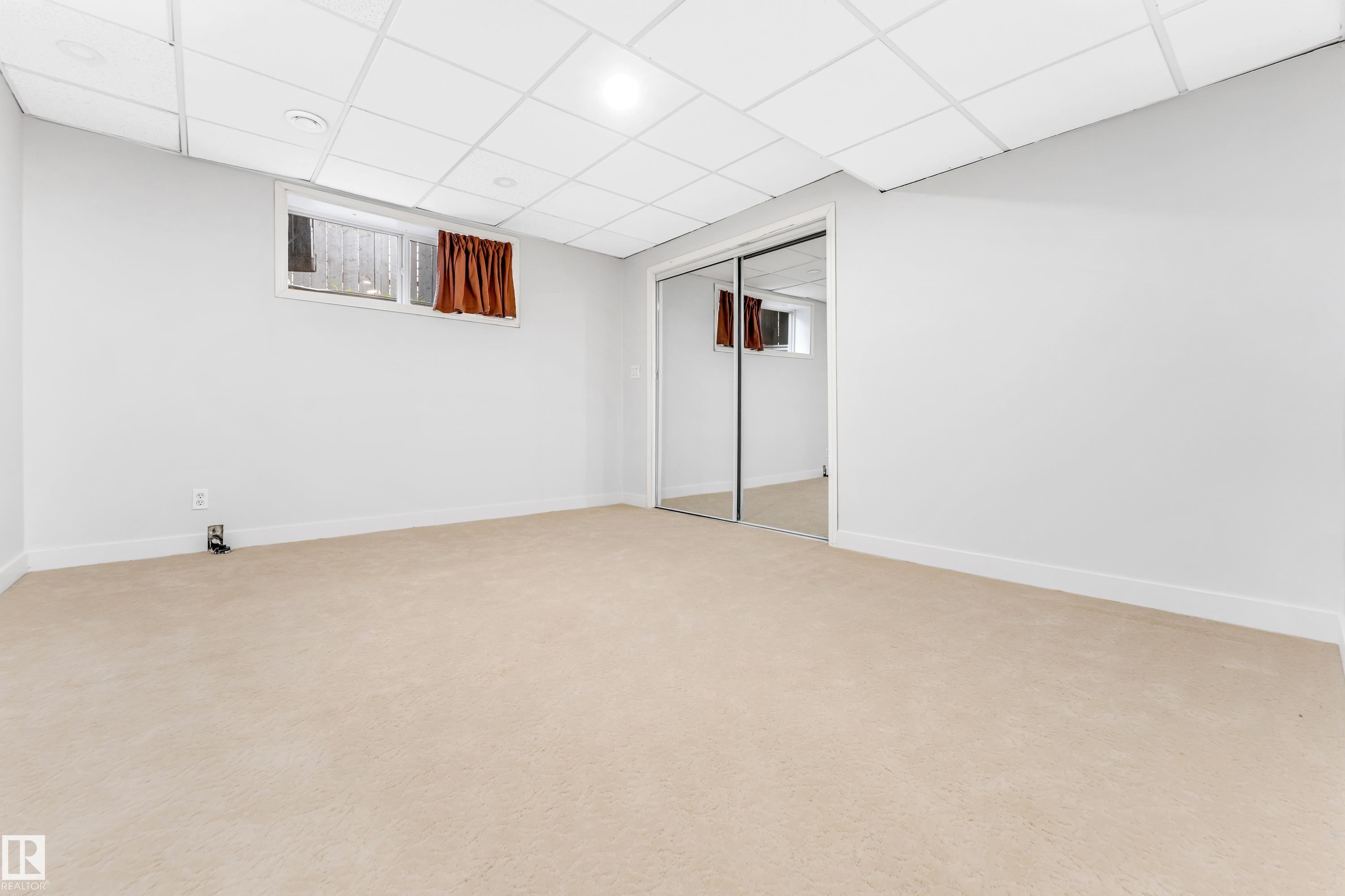 Spacious room featuring neutral carpeting, light-toned walls, and a drop ceiling with recessed lighting - 10621 175A Avenue, Edmonton, AB