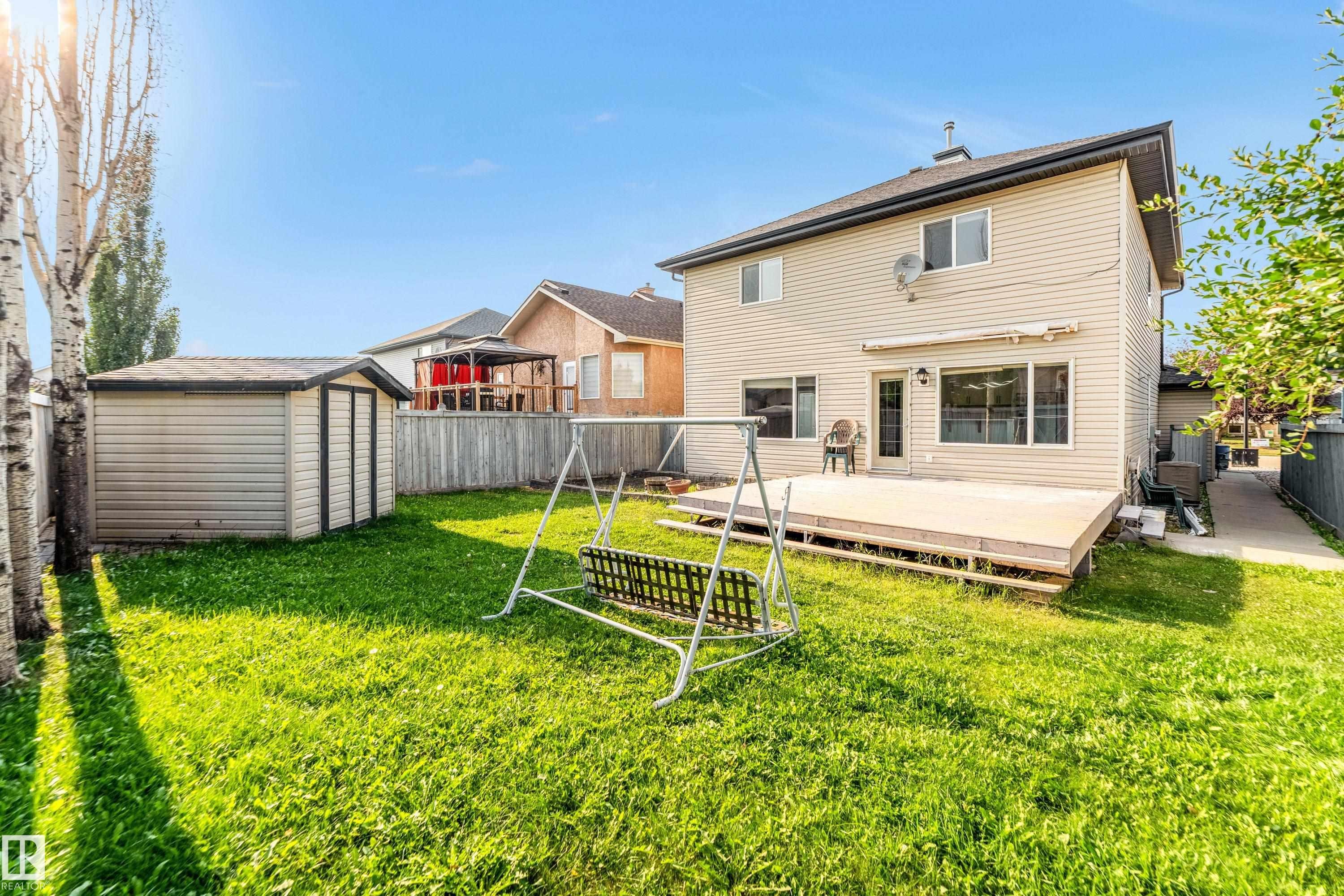 Expansive backyard featuring a manicured lawn, a detached storage shed, and mature trees - 10621 175A Avenue, Edmonton, AB