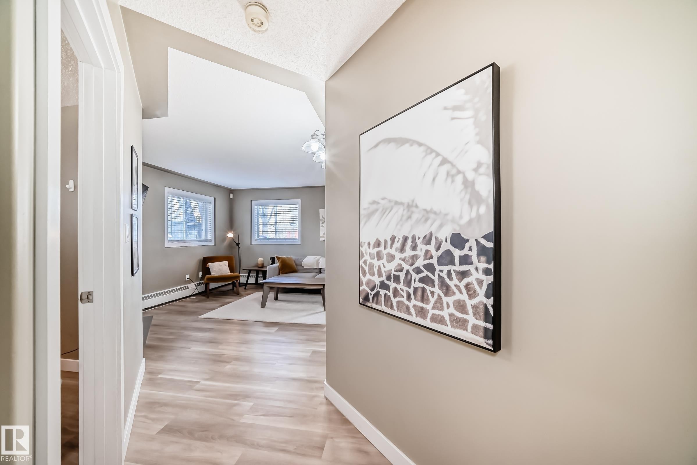 Bright interior space featuring wood-finish flooring, two windows, and neutral wall tones - 101 10827 85 Avenue Nw, Edmonton, AB - Indoor Photo Showing Other Room